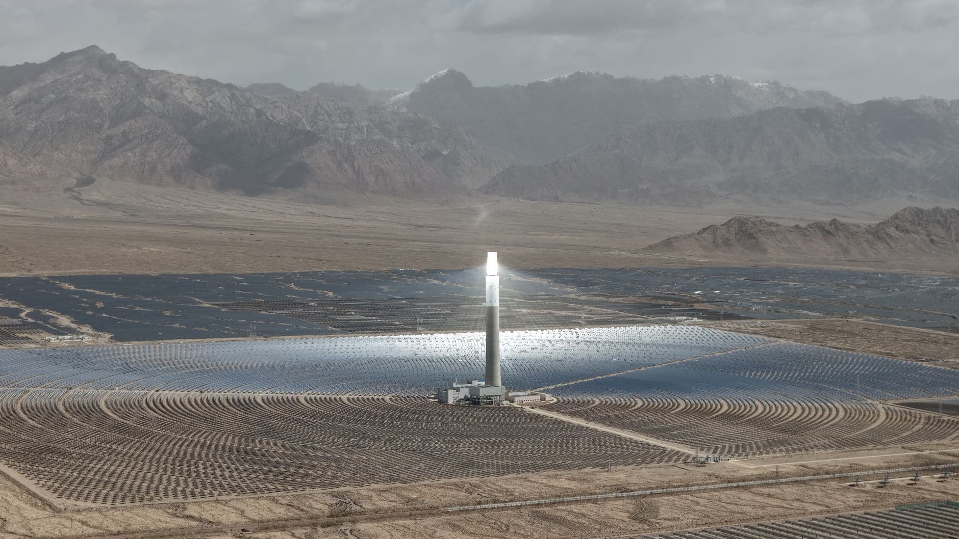 Centrala solara termica cu turn central inconjurata de mii de oglinzi heliostate, intr-un peisaj desertic cu munti, ilustrand industria de energie curata