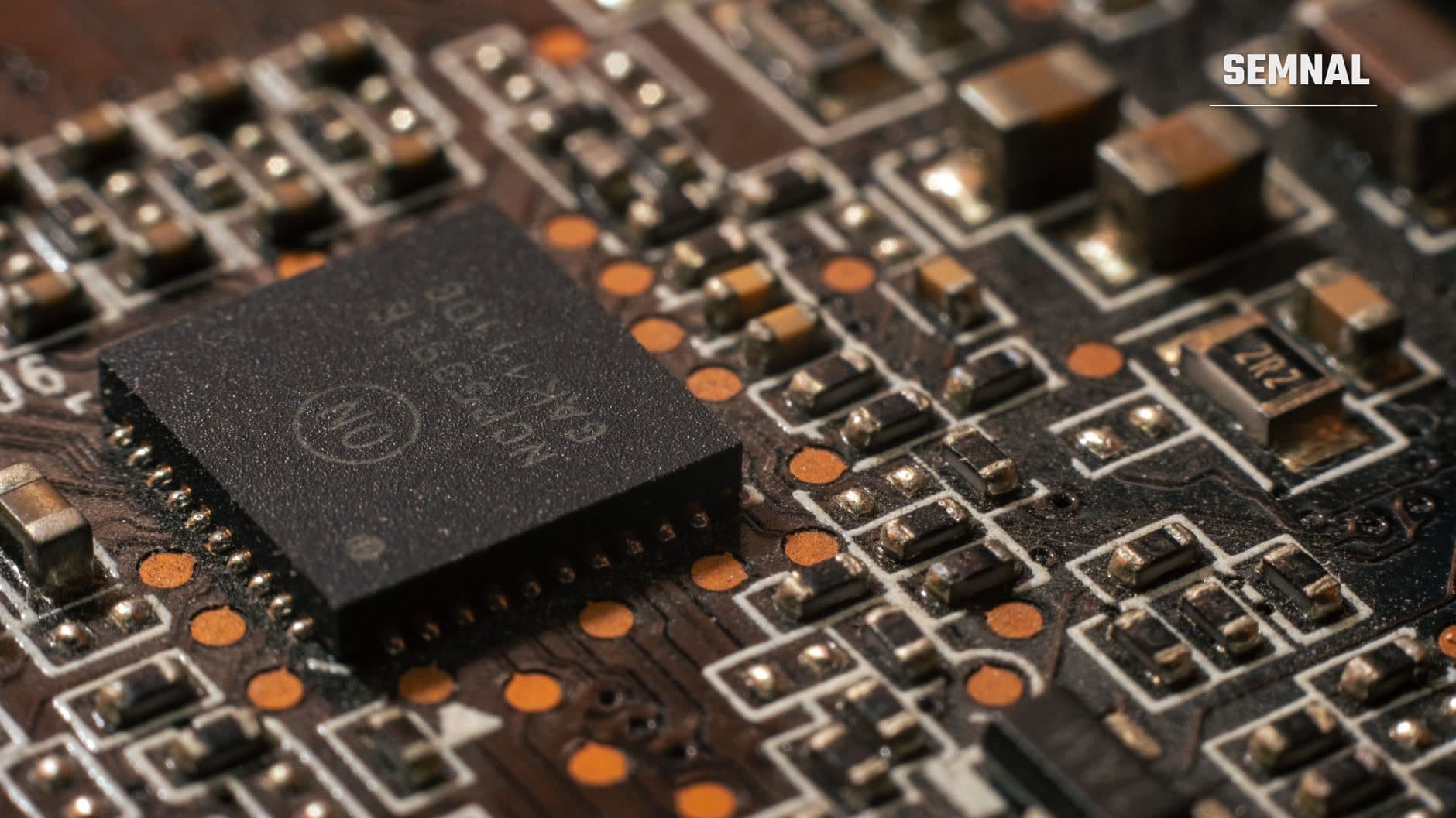 Detaliu macro al unei plăci de circuit cu cip negru și componente electronice colorate pe o matrice de circuite integrate, reprezentând tehnologia avansată a companiilor de inteligență artificială.