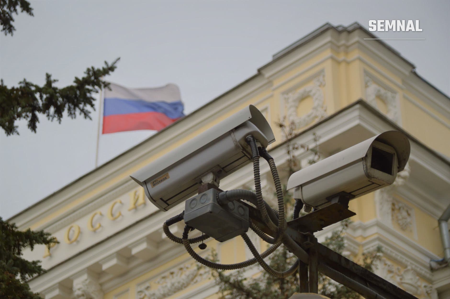 Camere de supraveghere pe o clădire oficială rusă cu steagul Rusiei, ilustrând controlul și supravegherea instituțională în contextul măsurilor de securitate guvernamentale.