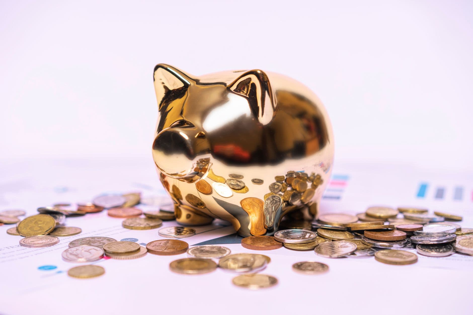 Pisică norocoasă aurie cu monede de aur și argint curgând din gură, pe fond cu grafice financiare, simbolizând economiile și creșterea banilor