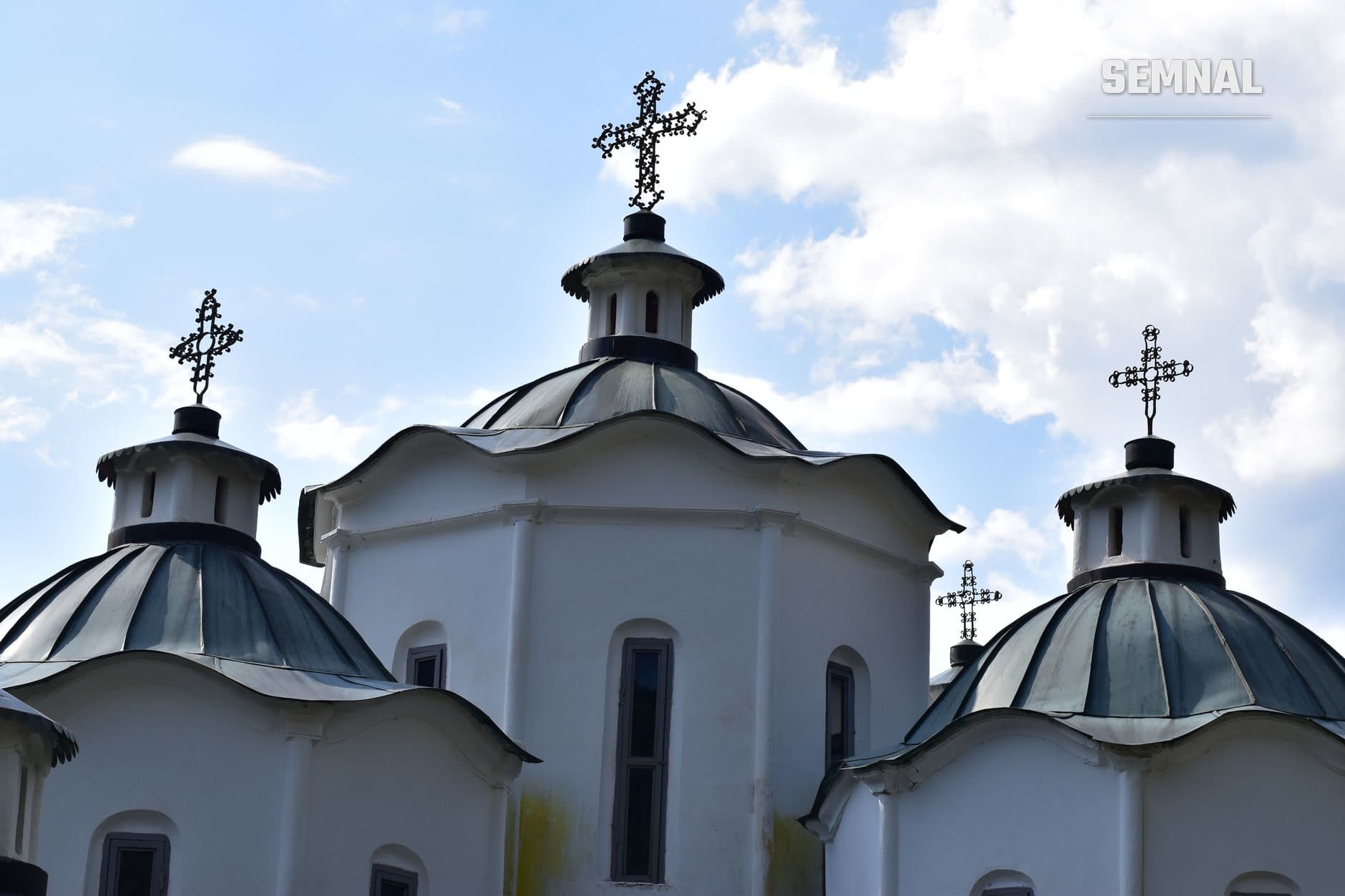 Trei domuri albe cu cruci ortodoxe negre și ornamentale, arhitectură religioasă bizantină caracteristică cultelor din Ucraina sub cer parțial noros.