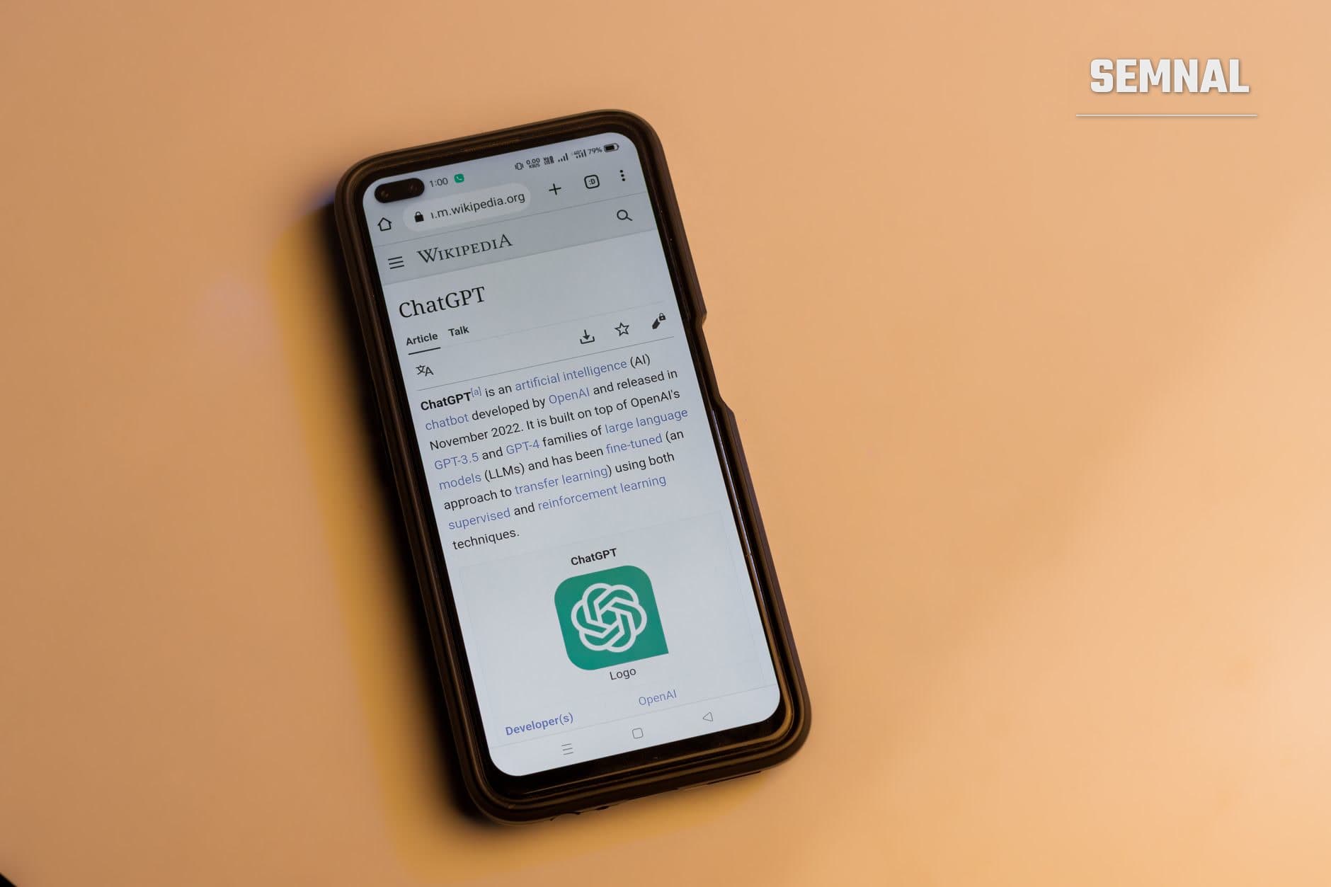 Ecran de telefon mobil afișând articolul Wikipedia despre ChatGPT cu logoul OpenAI verde și text despre dezvoltarea inteligenței artificiale și modelele de limbaj.