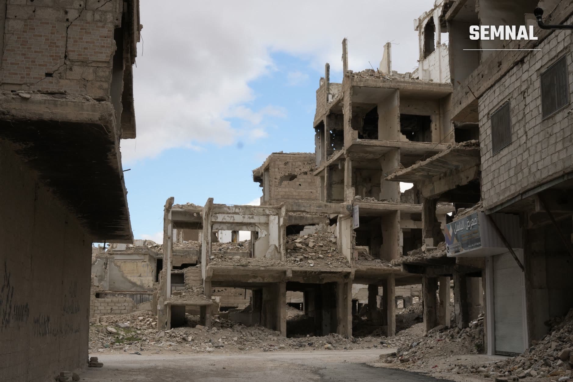 Clădiri devastate de bombardamente în apropierea unui sector din Gaza, cu structuri de beton distruse, ferestre sfărâmate și moloz peste sol, ilustrând daunele militare