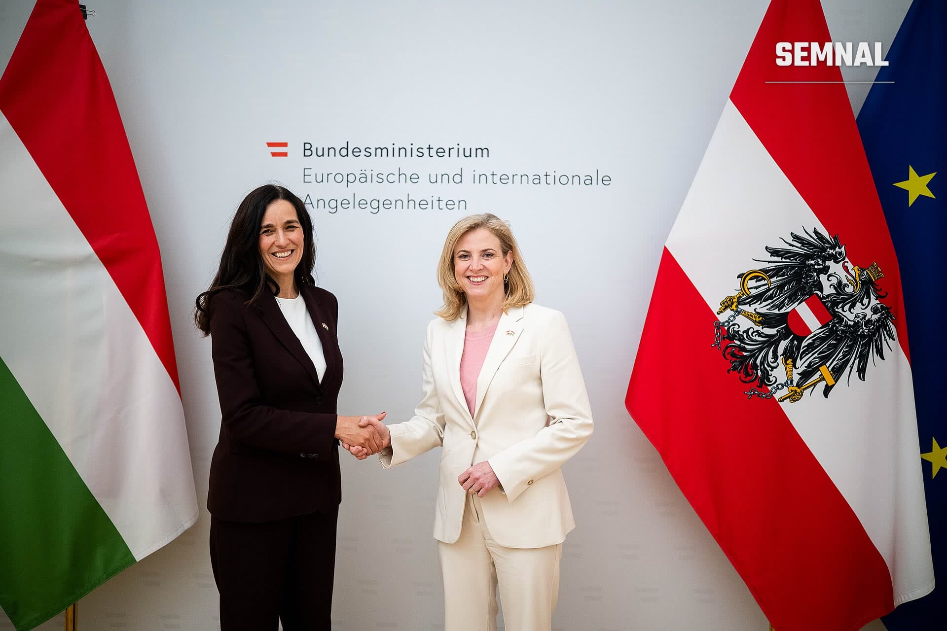 Anita Orban, ministrul de externe și vicepremier al Ungariei, strânge mâna cu o oficială austriacă la o întâlnire diplomatică oficială, în fața steagurilor Austriei și Ungariei. (Foto: Bundesministerium für europäische und internationale Angelegenheiten)