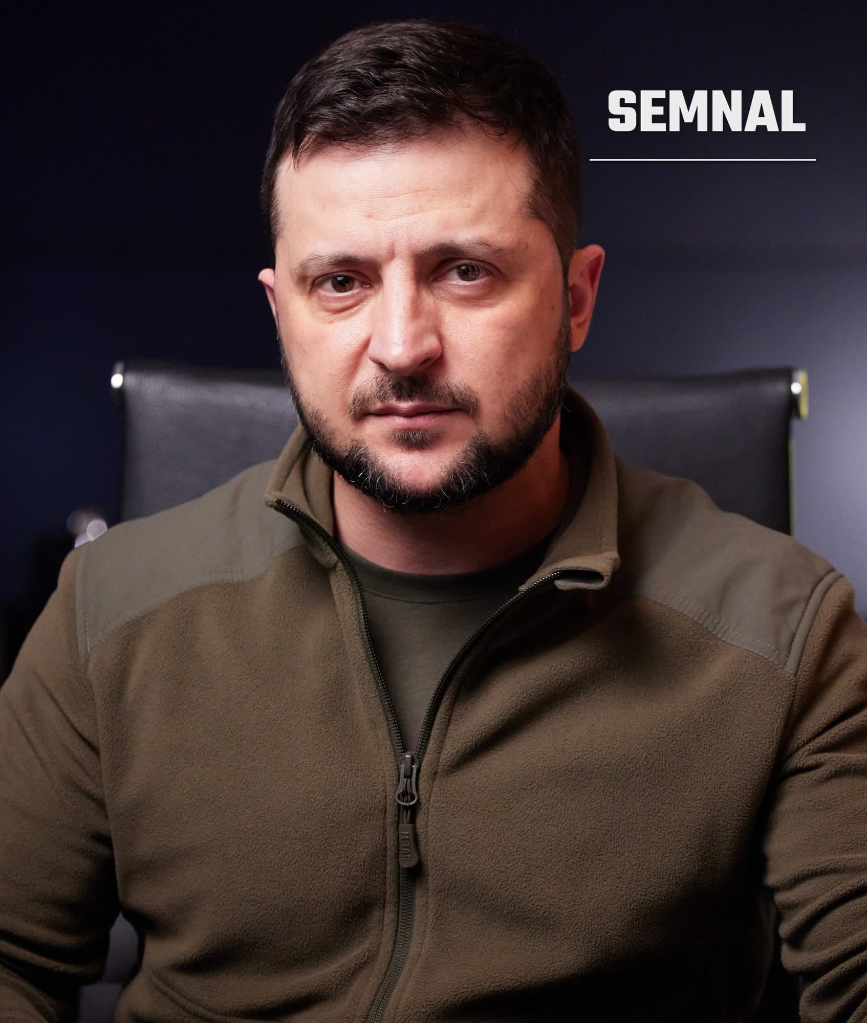 Volodimir Zelenski, președintele Ucrainei, portretu frontal într-o jachetă kaki, cu expresie serioasă în fața unui fond negru (Foto: President of Ukraine from Україна)