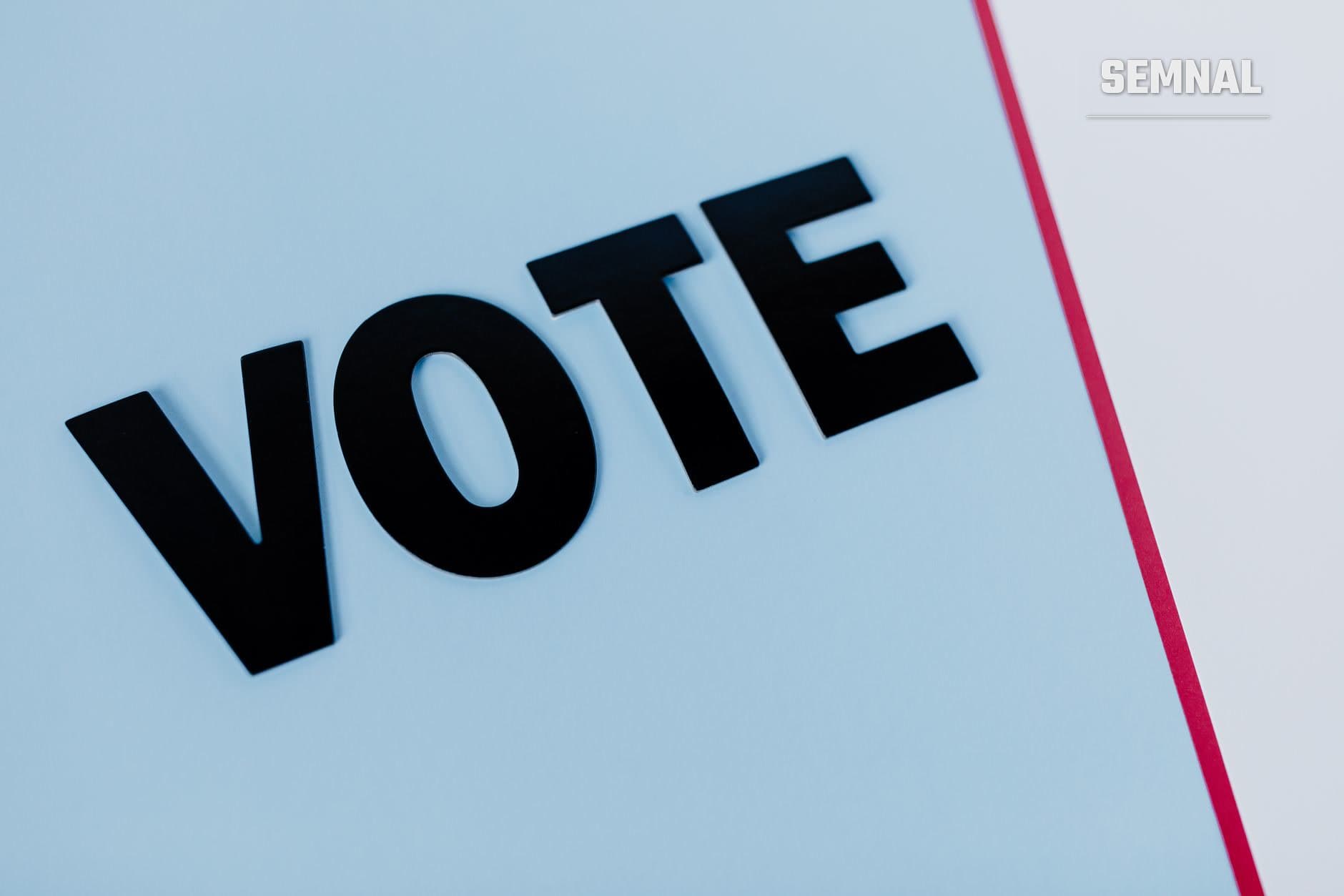Cuvântul "VOTE" în litere negre tridimensionale pe fundal albastru clar, cu o linie roz pe dreapta, ilustrând conceptul de votare și alegeri. (Foto: Tara Winstead / Pexels)