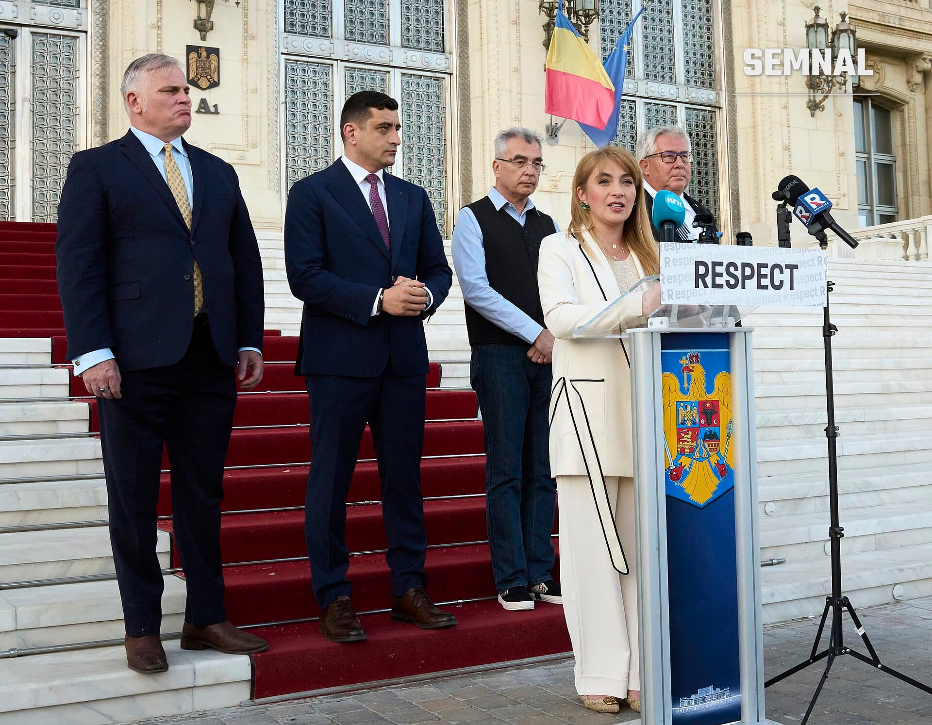 George Simion, vorbitor la o conferință de presă pe scările unei instituții oficiale, alături de alți patru membri ai delegației, în fața steagurilor României și Uniunii Europene. (Foto: AUR România)