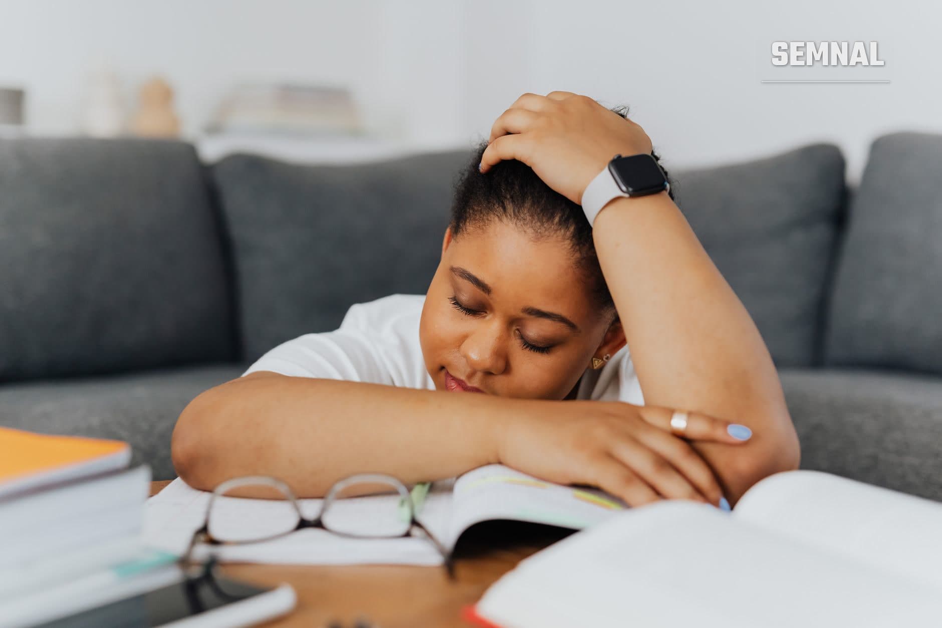 Femeie obosită sprijinind capul în mână la o masă de lucru, purtând smartwatch, cu expresie de epuizare și oboseală cronică. (Foto: https://kaboompics.com/ / Pexels)