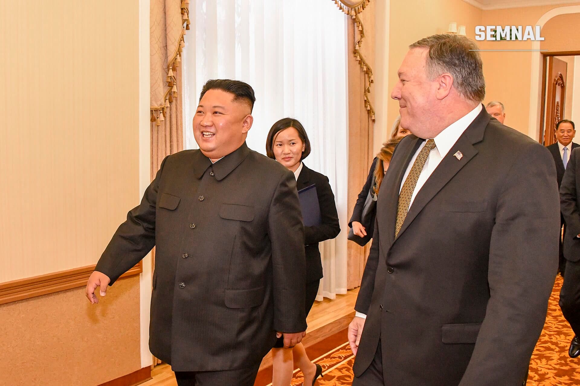 Kim Jong-un, în costum militar negru, se află în prim-plan la o întâlnire oficială în interior, într-o sală elegant decorată cu draperii și ornamente aurii. (Foto: U.S. Department of State from United States)