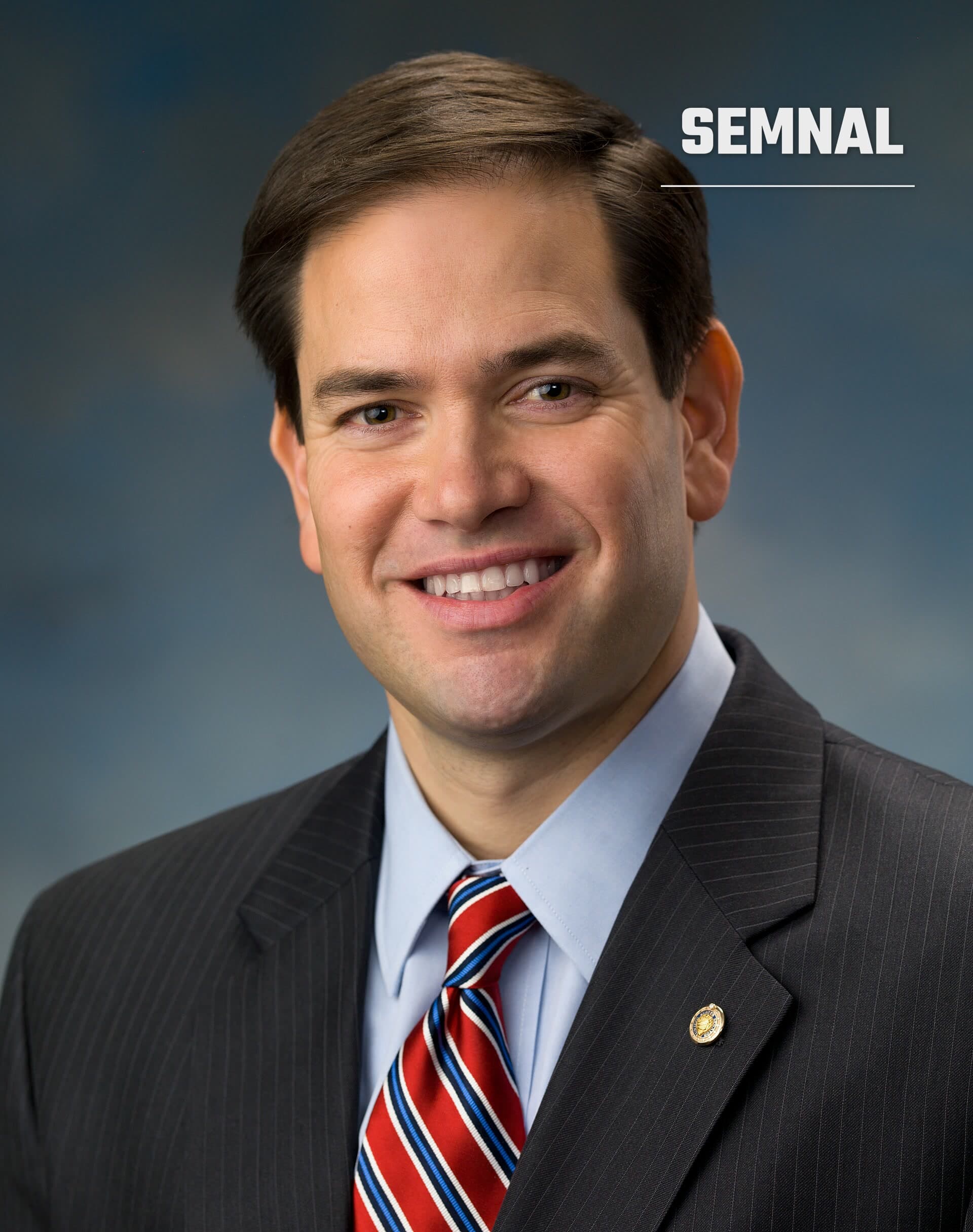 Marco Rubio, secretarul de stat american, în portret de presă cu costum gri și cravată roșu-albastru pe fundal gri neutru. (Foto: US Senate)