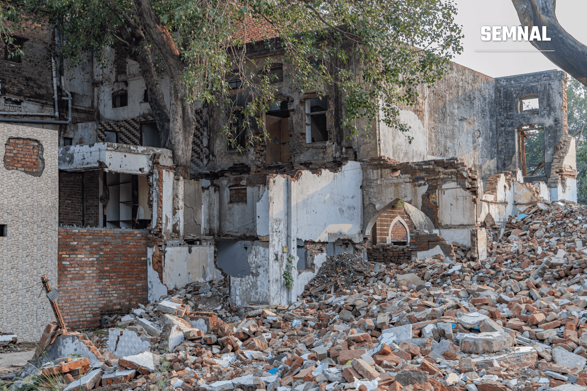 Clădiri distruse și moloz din cărămidă roșie și beton rămas după raiduri aeriene, cu pereți prăbușiți și vegetație pe structurile abandonate în zona unui conflict armat. (Foto: Shantum Singh / Pexels)