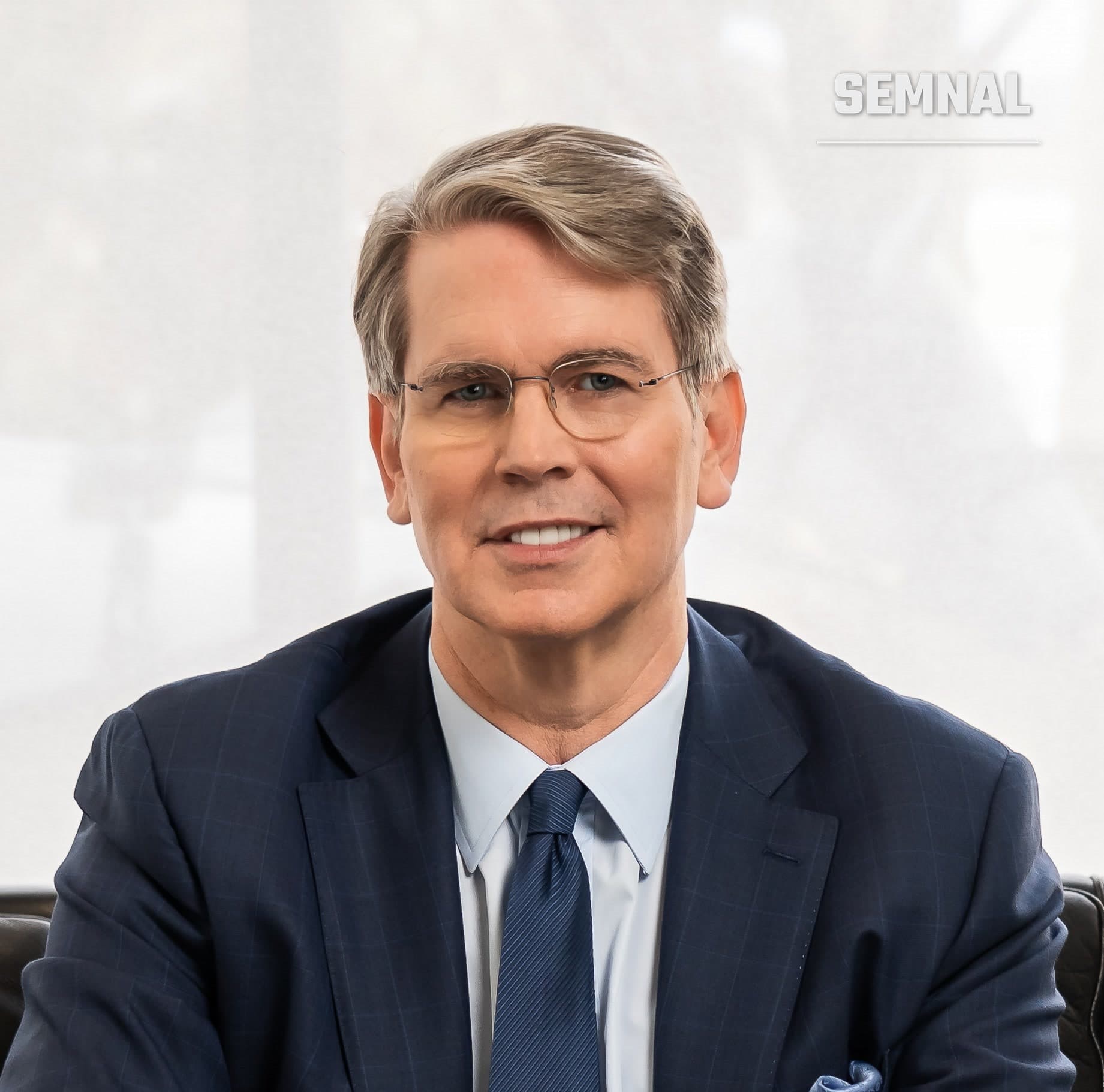 Scott Bessent, portret de presa, barbat cu ochelari, imbracat formal intr-un costum bleumarin cu camasa alba si cravata bleumarina, pe fond neutru (Foto: Treasury Department)