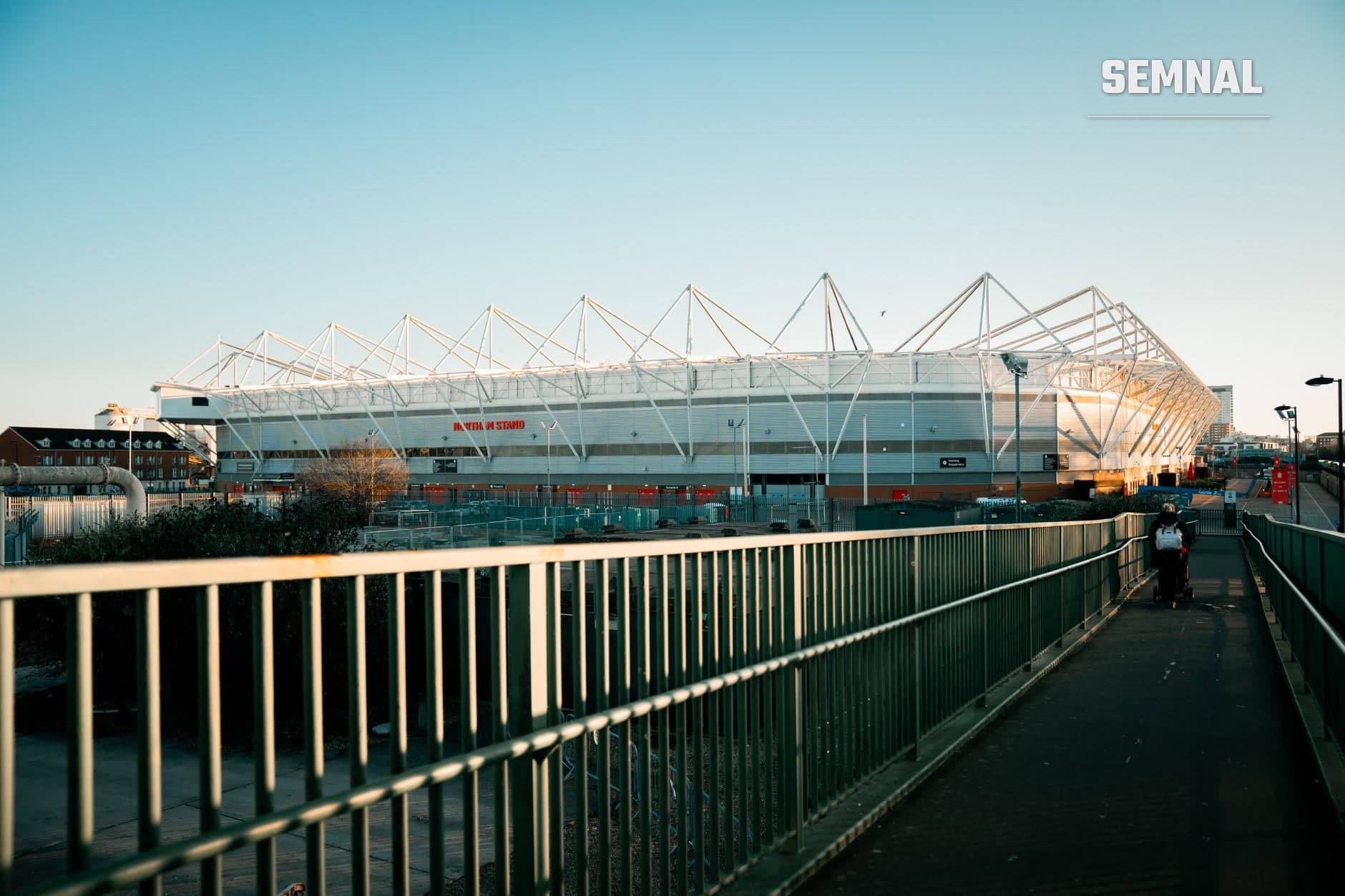 Stadionul Etihad al Manchester City, cu structura caracteristică a acoperișului susținut de cabluri tensionate, fotografiat din exterior în lumina zilei. (Foto: GMB VISUALS / Pexels)