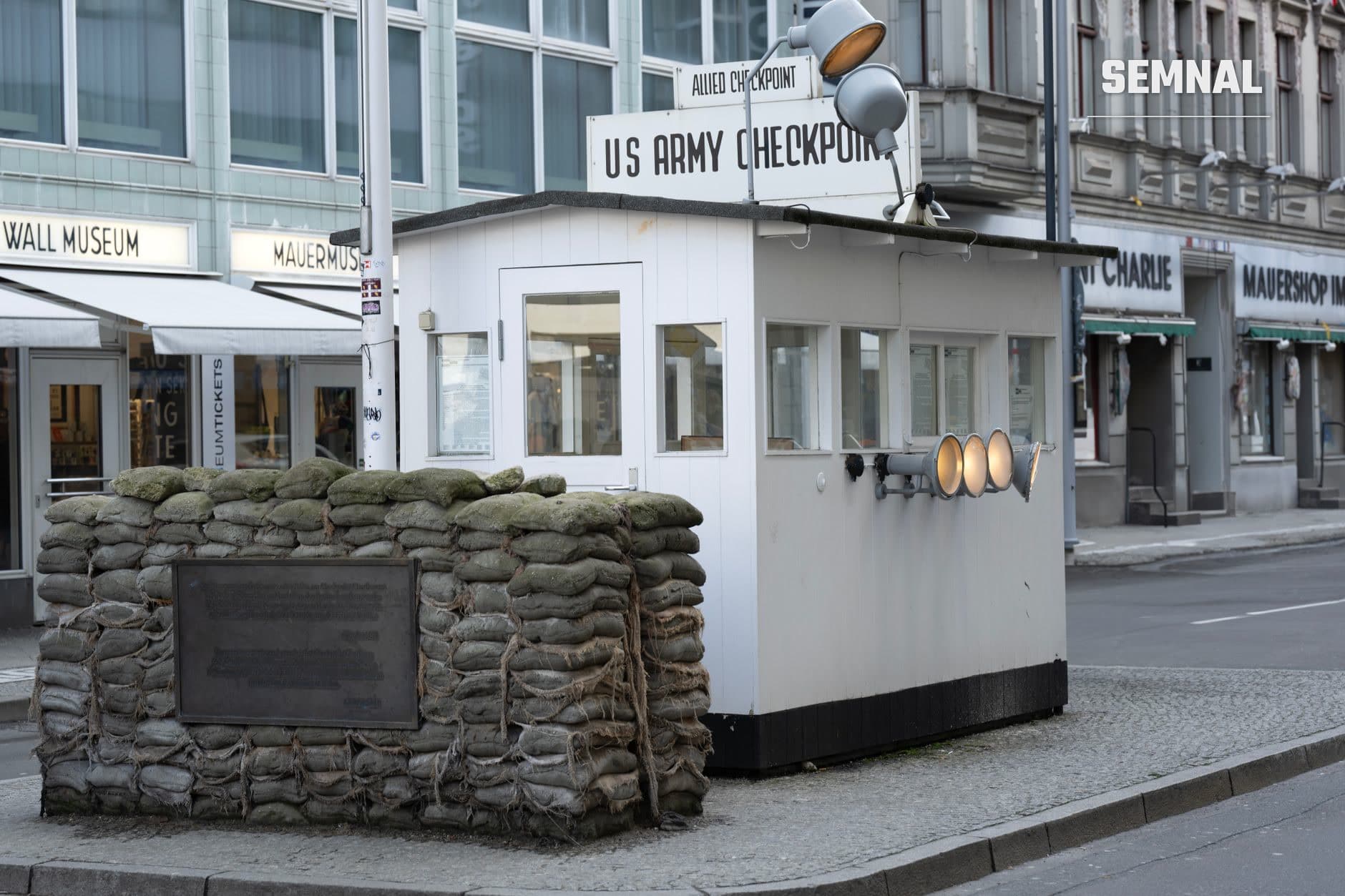Postul de control Checkpoint Charlie la Berlin, cu cabana de gardă albă și saci de nisip, simbol al controalelor la frontiere și securității internaționale în Germania (Foto: Miguel Cuenca / Pexels)