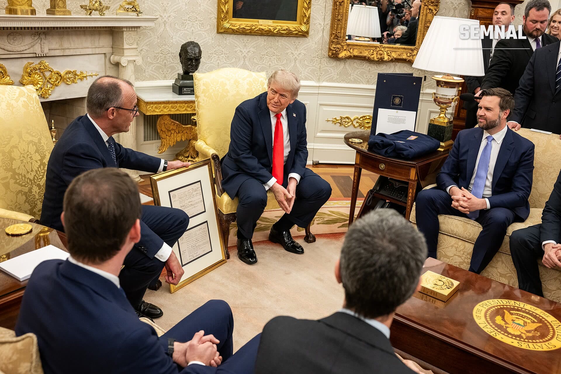 Friedrich Merz, în costum bleumarin cu cravată roșie, în discuții officiale într-un birou de stat elegant, alături de alți oficiali. (Foto: The White House)