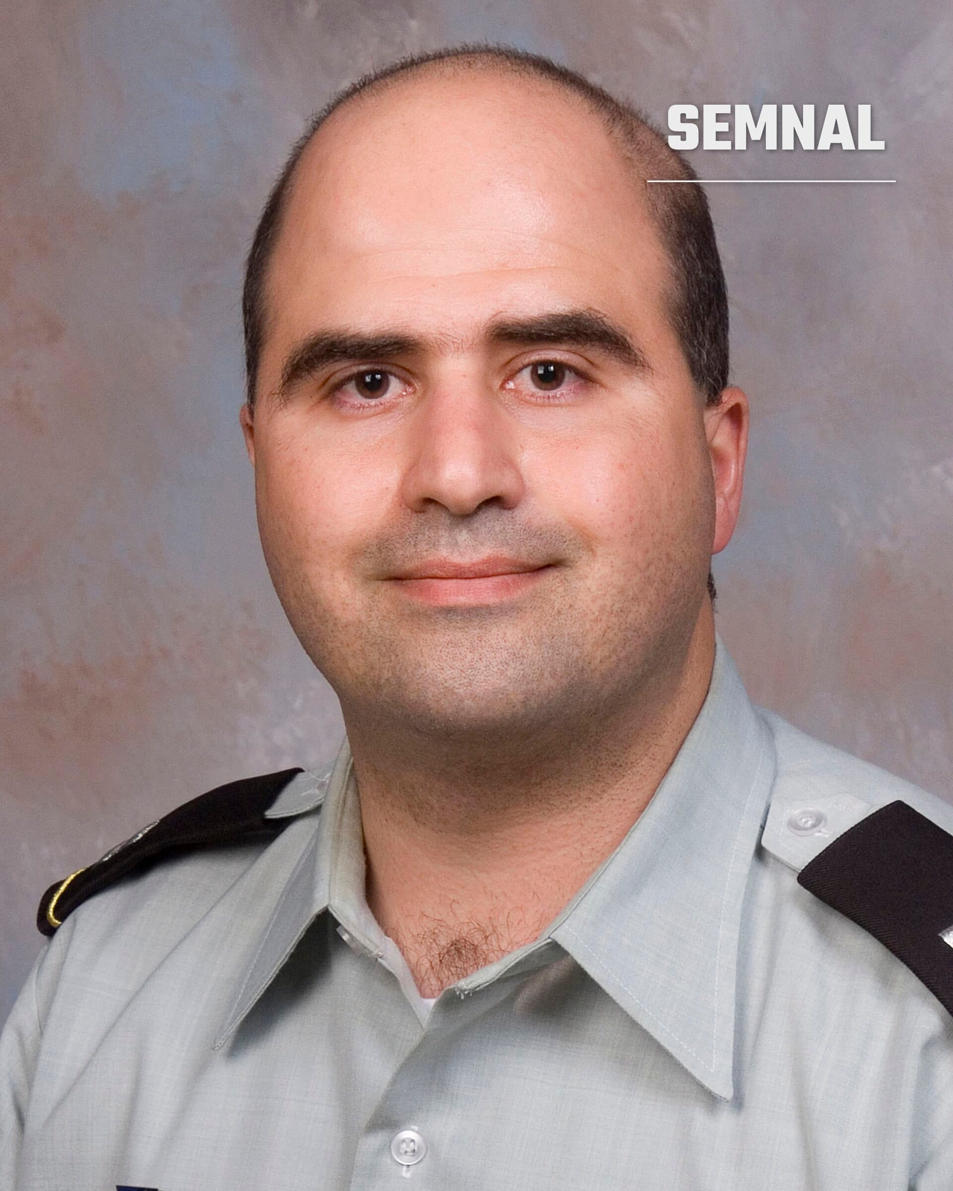 Nidal Hasan, fost maior al armatei americane, in portret oficial purtand uniforma militara gri-bej cu insigne pe umeri, pe fundal gri-albastru neutru. (Foto: Uniformed Services University of the Health Sciences)