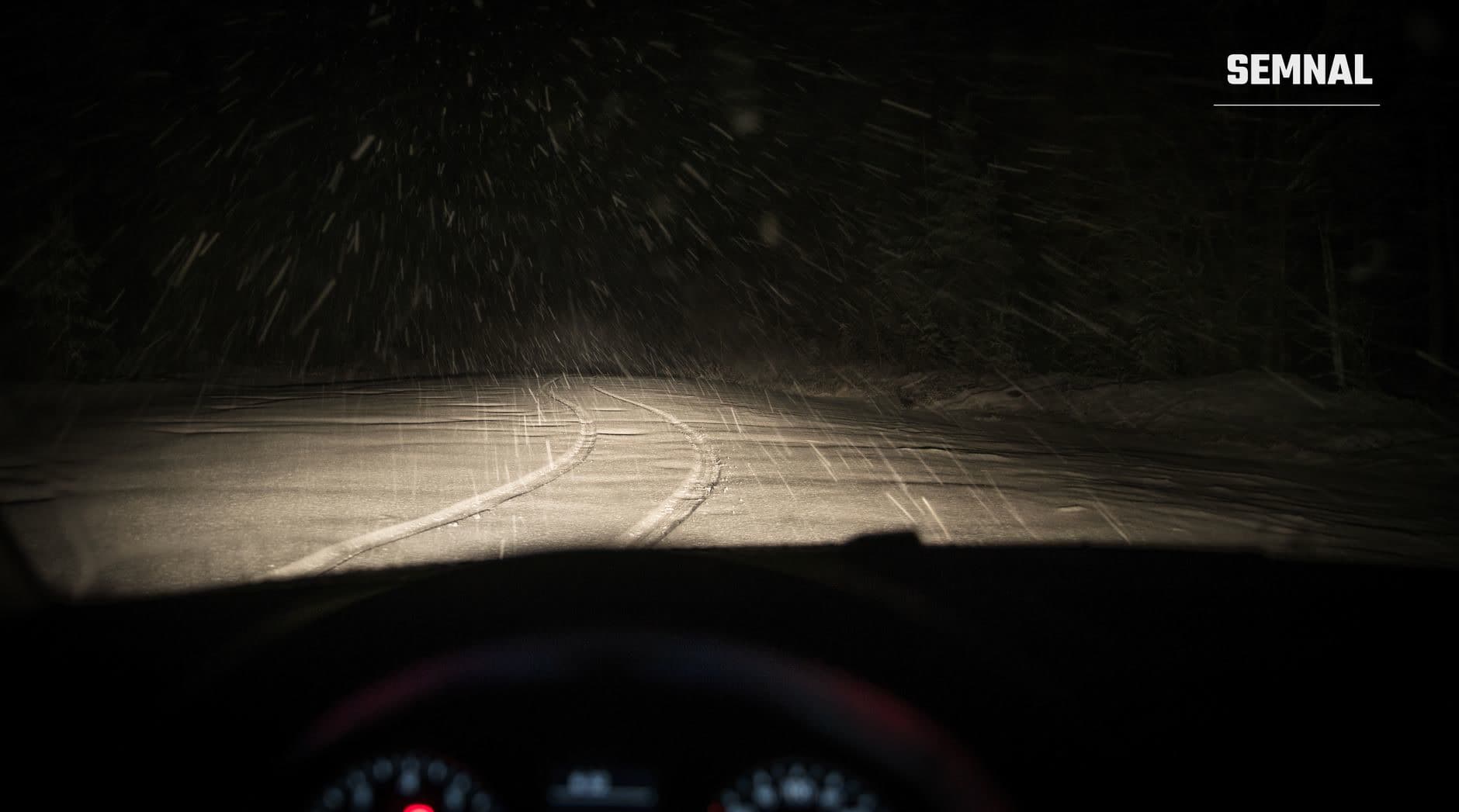 Șosea acoperită cu zăpadă și polei văzută noaptea din cabina unui vehicul, cu farul care iluminează drumul plin de urme și condiții meteo dure. (Foto: Egor Kamelev / Pexels)
