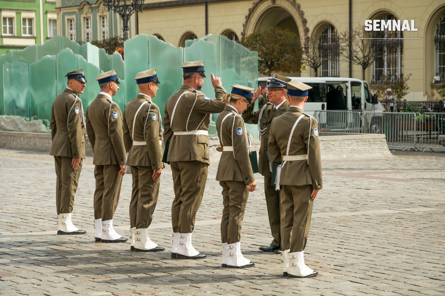 Ofițeri militari români în uniformă de ceremonie în formație pe o piață publică, cu clădiri istorice și baricade de securitate în fundal. (Foto: SHOX ART / Pexels)