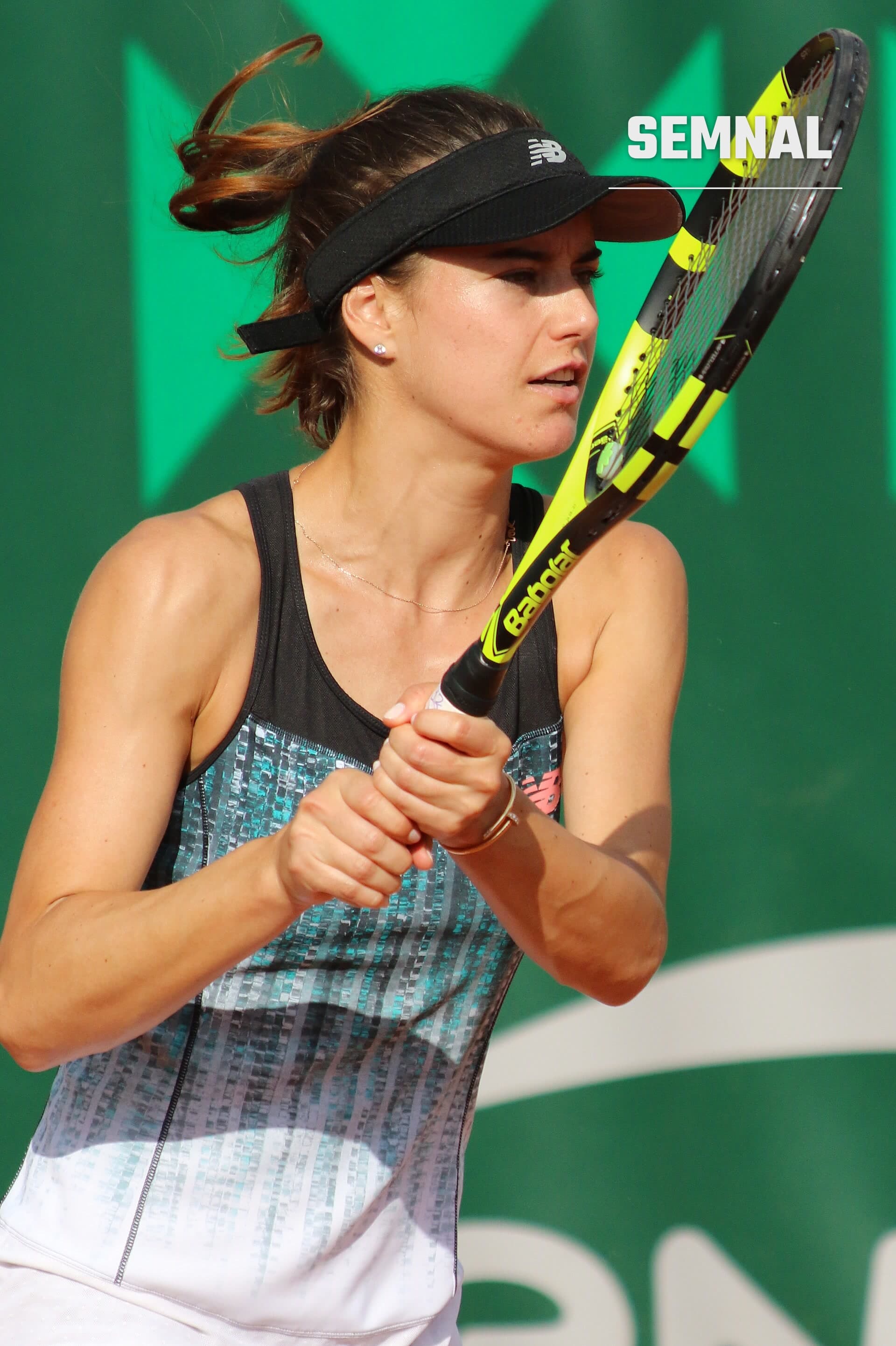Sorana Cîrstea, jucătoare de tenis, în profil pe terenul de joc, purtând vizieră și ținută de sport, ținând o rachetă galbă, fundal verde (Foto: si.robi)