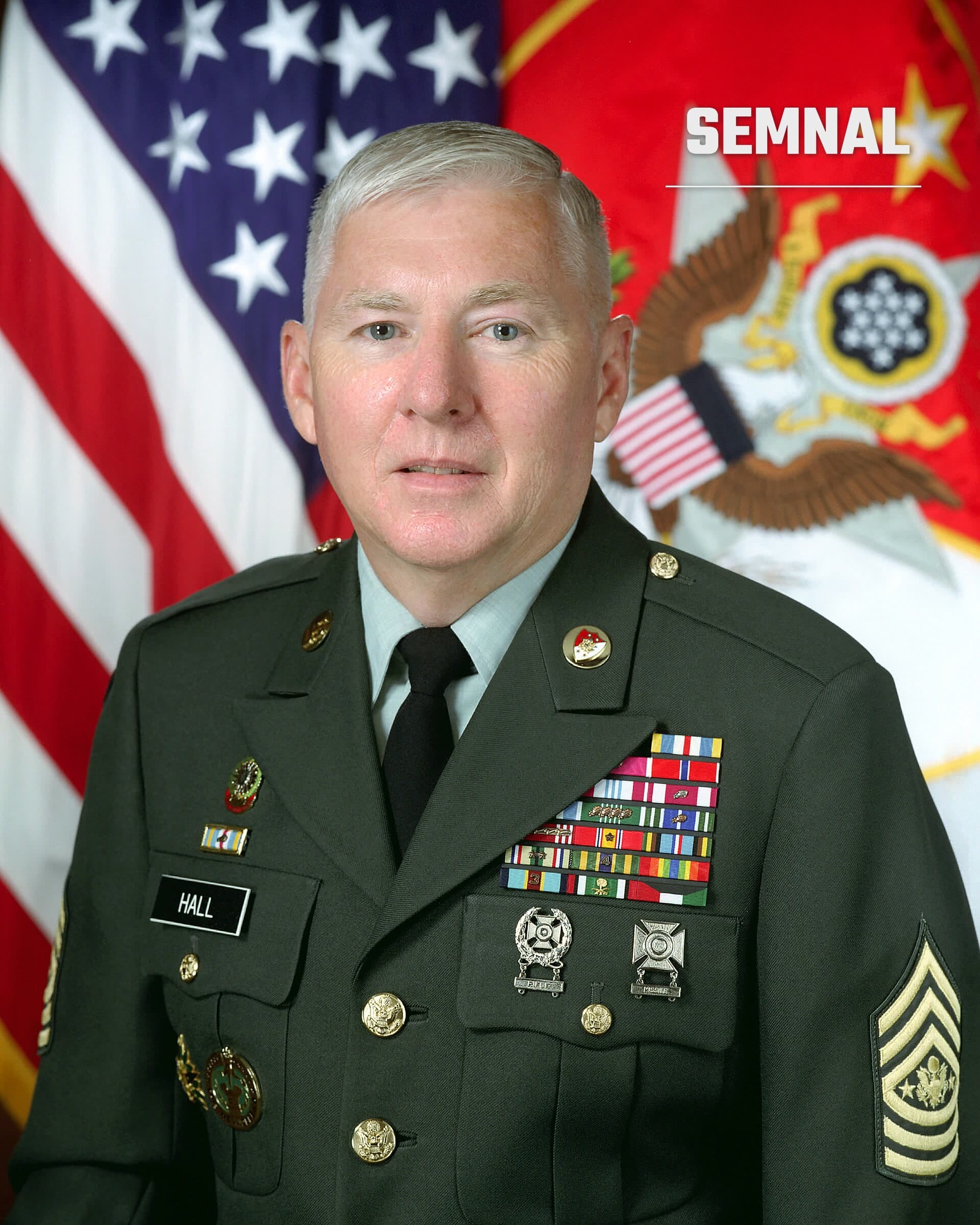Robert E. Hall în uniformă militară oficială cu decorații și insigne, portret de presa cu drapelul american în fundal. (Foto: US gov)