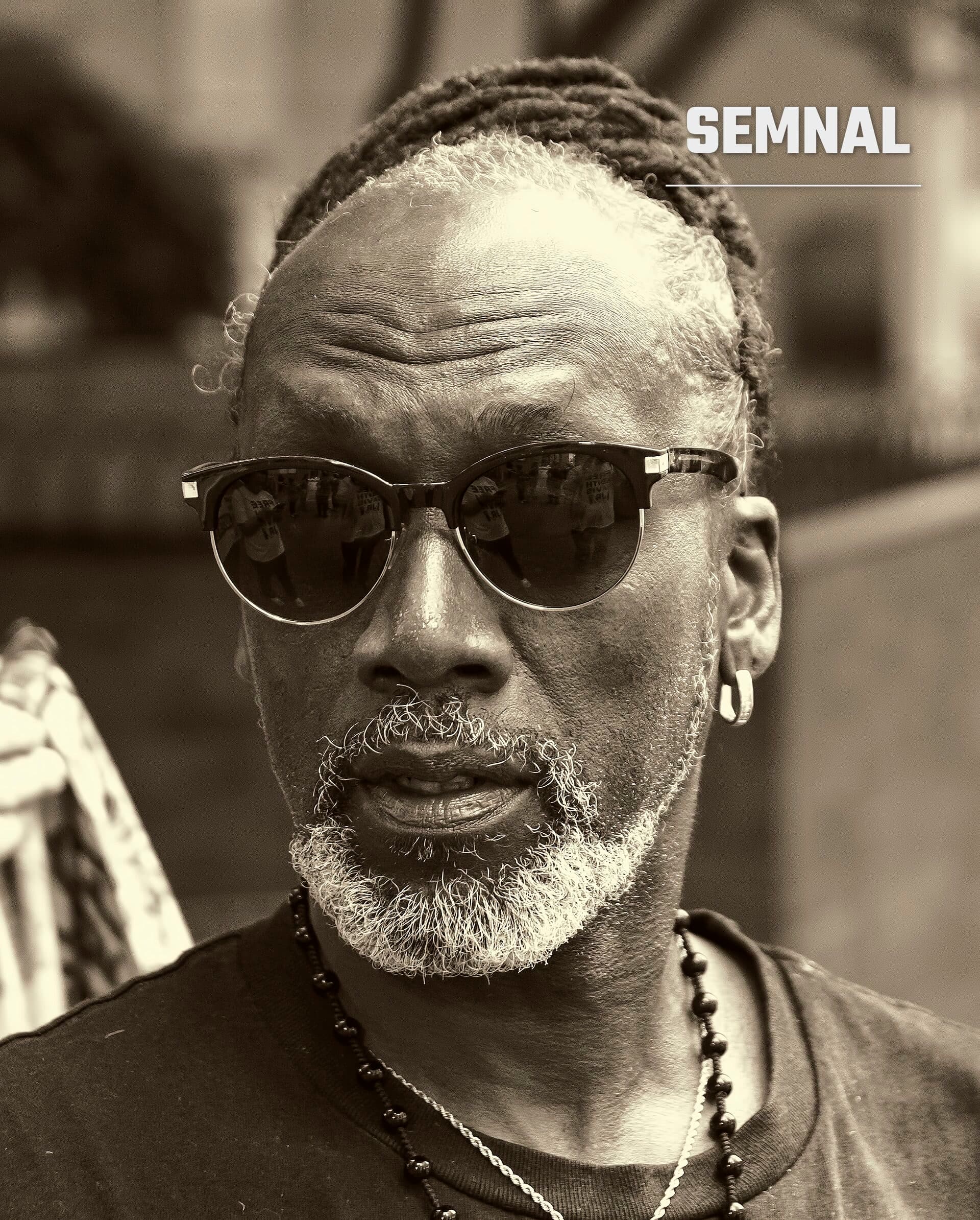 Duane Davis, portret în alb-negru cu ochelari de soare și barbă gri, îmbrăcat în tricou negru cu lanț de mărgele (Foto: Bruce Emmerling)