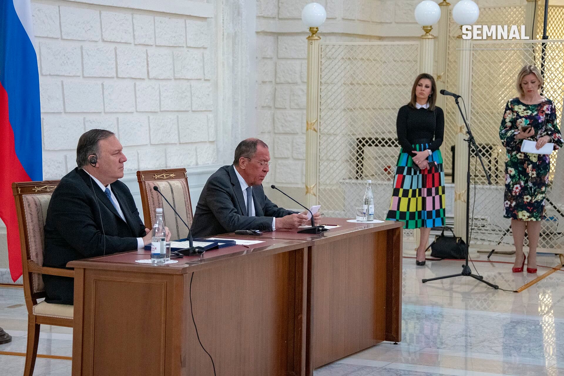Maria Zaharova, purtătoarea de cuvânt, stând în picioare la o conferință în sală cu decorații elegante, îmbrăcată în rochie neagră și fustă colorată. (Foto: U.S. Department of State from United States)
