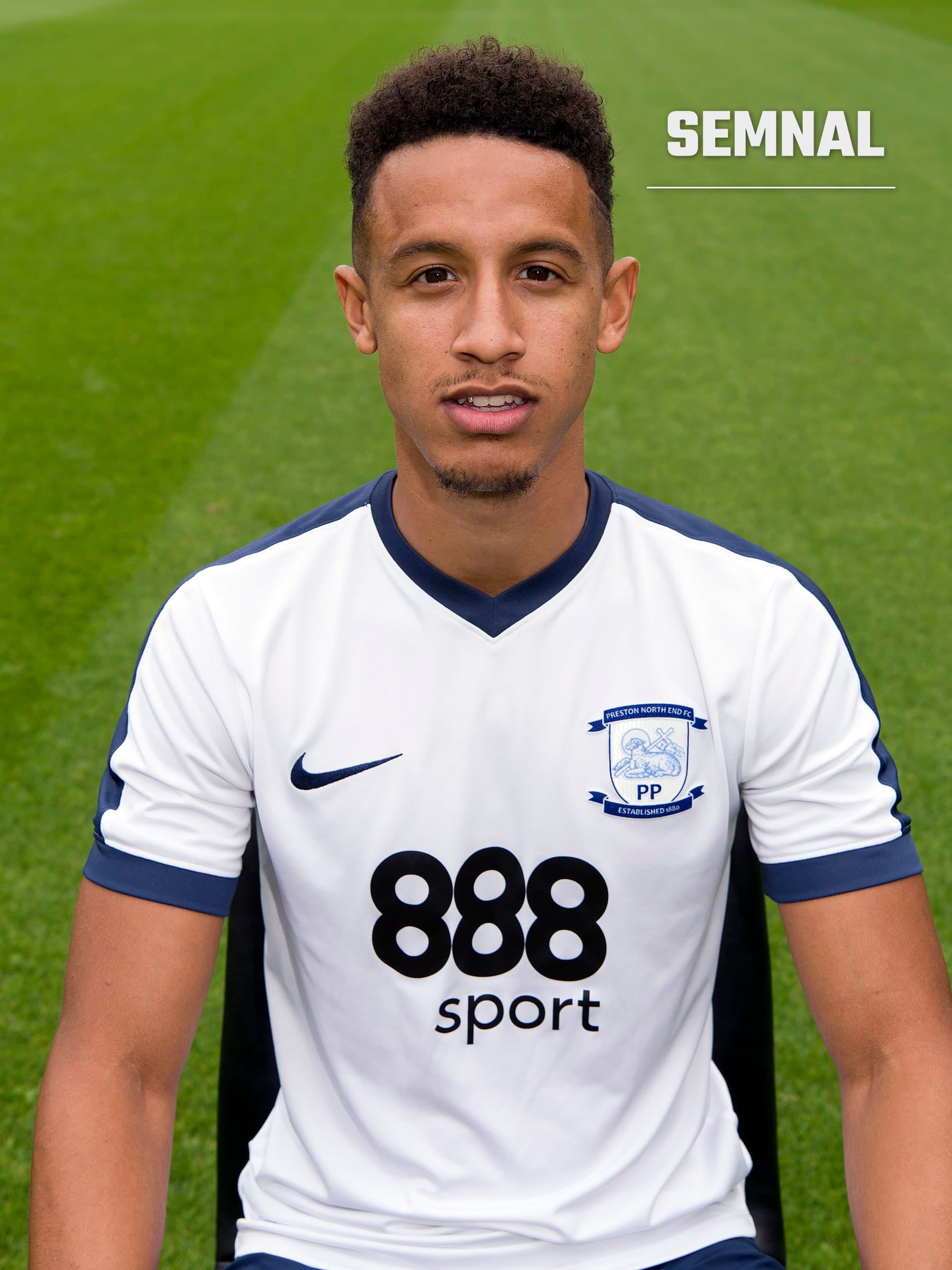 Callum Robinson, într-un tricou alb cu detalii albastru-închis, așezat în fața unui teren de iarbă verde. (Foto: Preston North End F.C.)