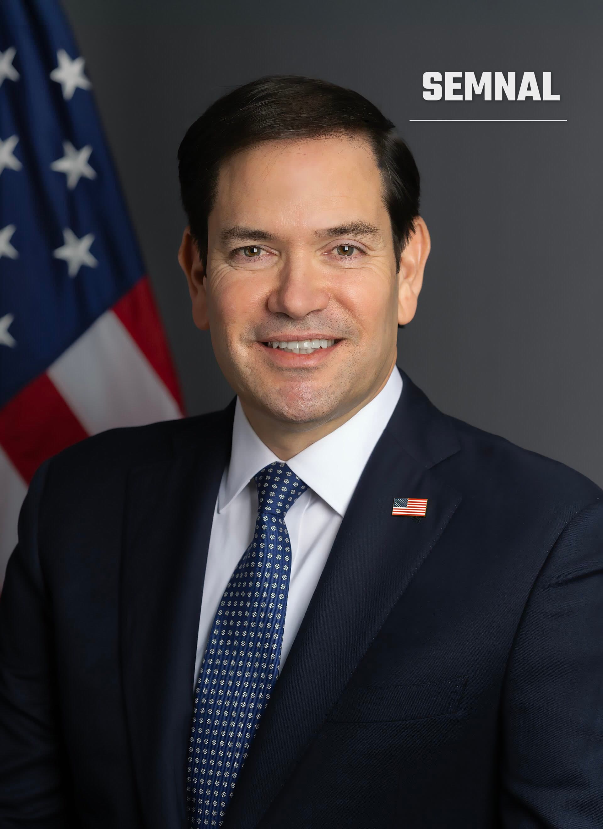 Marco Rubio, secretarul de stat al SUA, într-un portret oficial în costum bleumarin, cu steagul american în fundal. (Foto: U.S. Department of State)