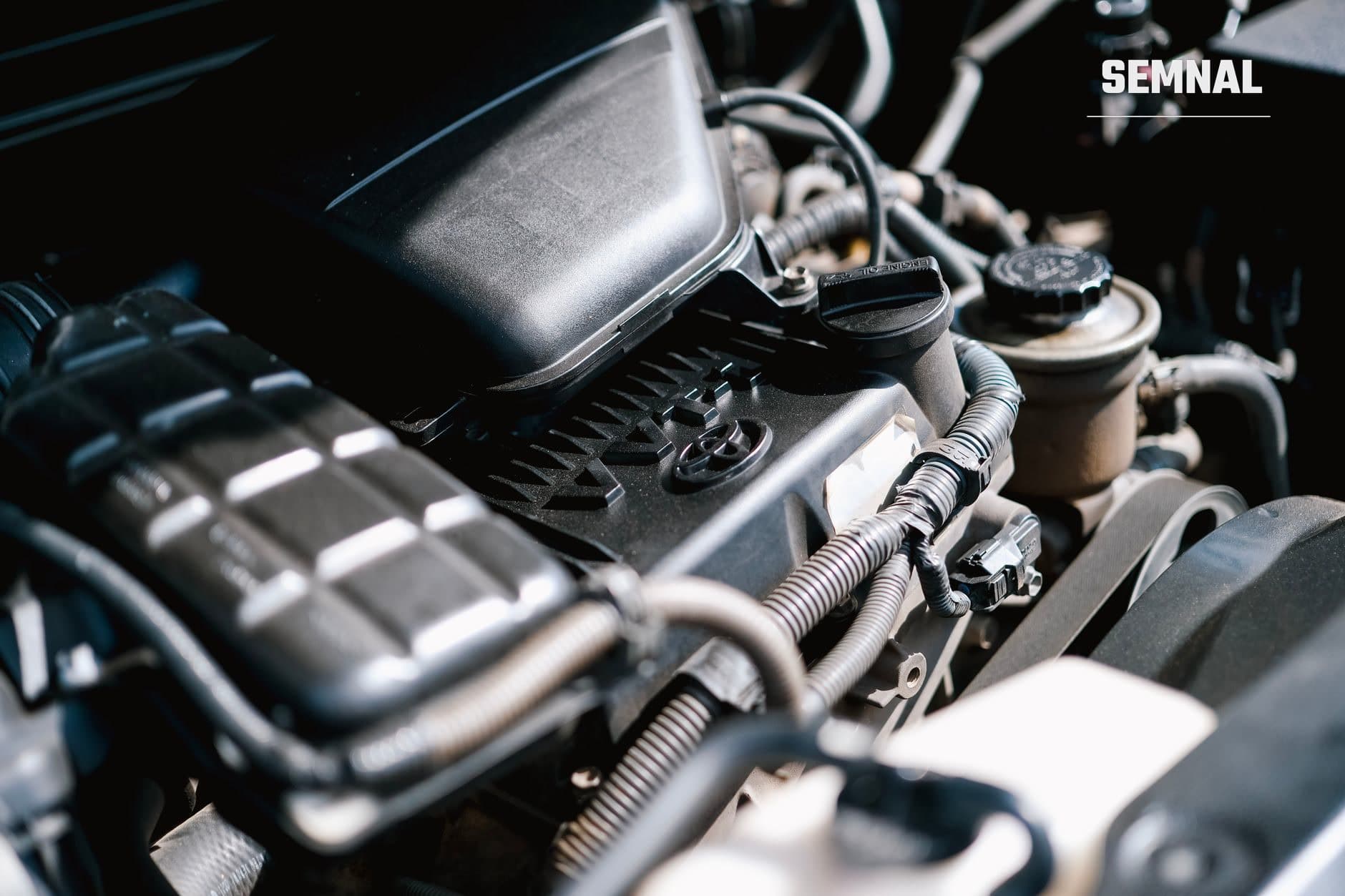 Compartimentul motorului unui automobil, cu capac negru din plastic, buson de ulei, rezervor de lichid de răcire și cabluri electrice. (Foto: Ayyeee Ayyeee / Pexels)