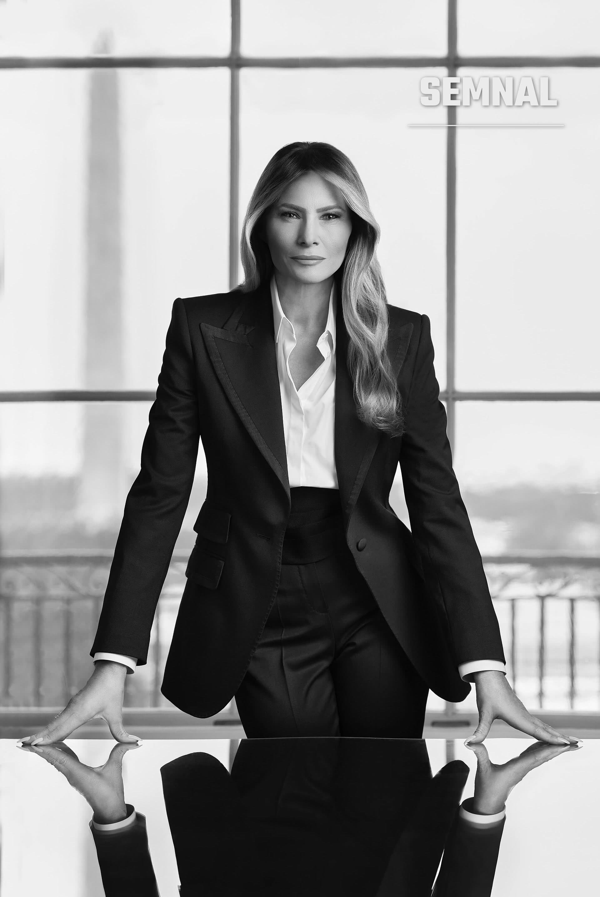 Melania Trump, în costum negru și cămașă albă, sprijinită de o masă lucioasă, în fața ferestrelor mari, în alb-negru. (Foto: Régine Mahaux)