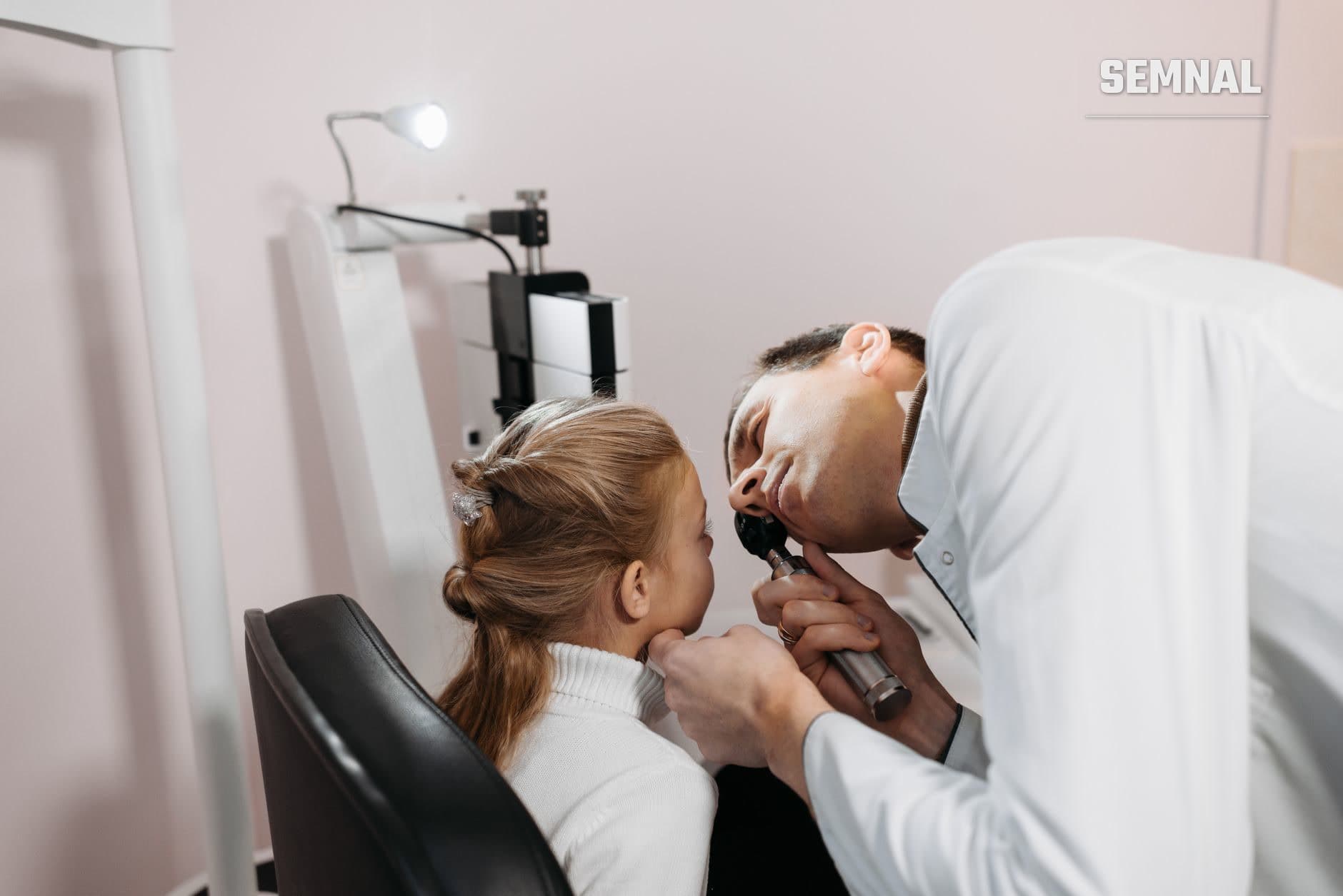 Medic în halat alb examinează urechea unei fetițe cu un otoscop, într-un cabinet medical. (Foto: Pavel Danilyuk / Pexels)