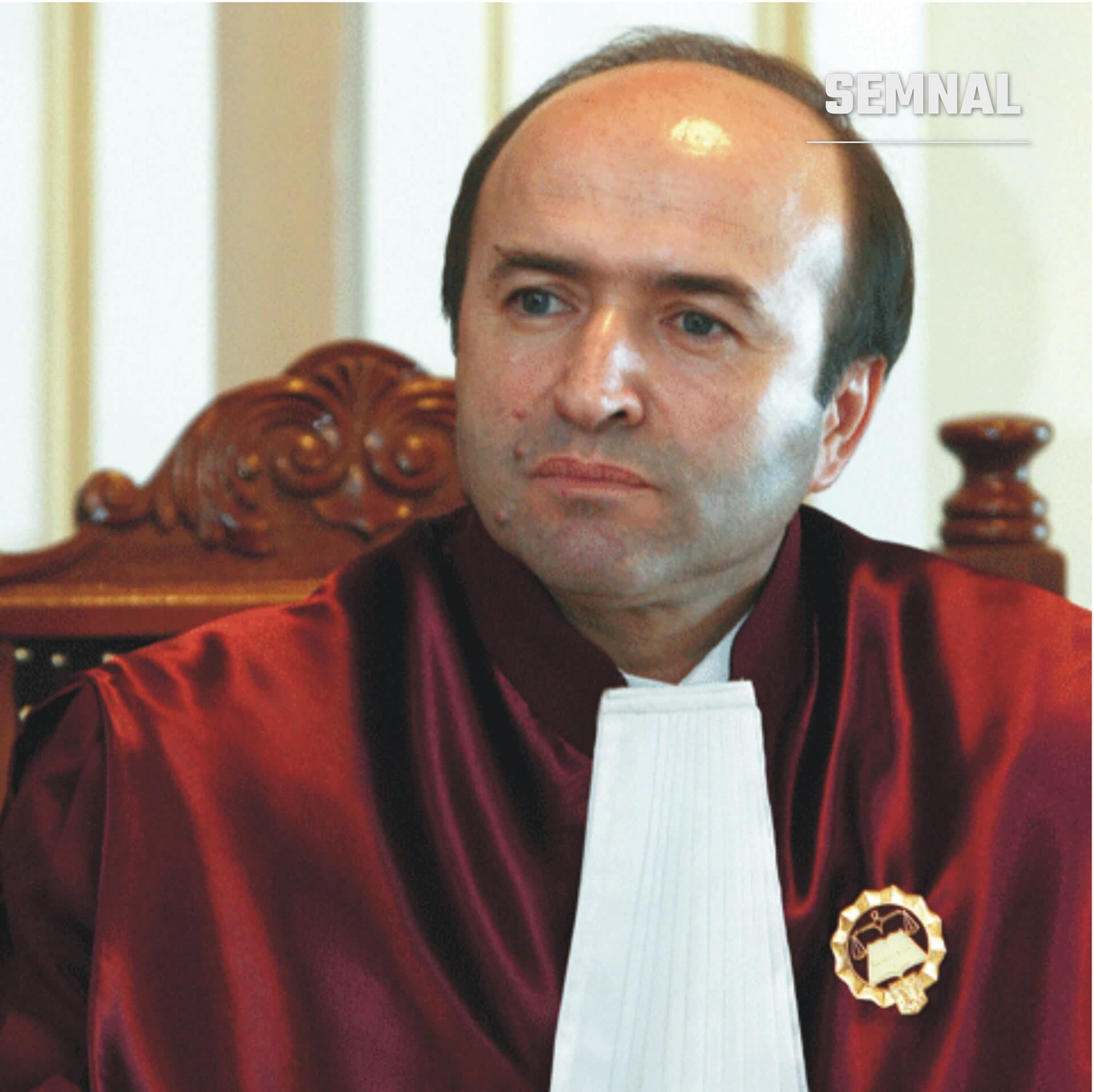 Tudorel Toader, fostul ministru al Justiției, în robă roșie de magistrat, cu banda albă și insigna aurie, într-un fotoliu de lemn sculptat. (Foto: Webmstrup)