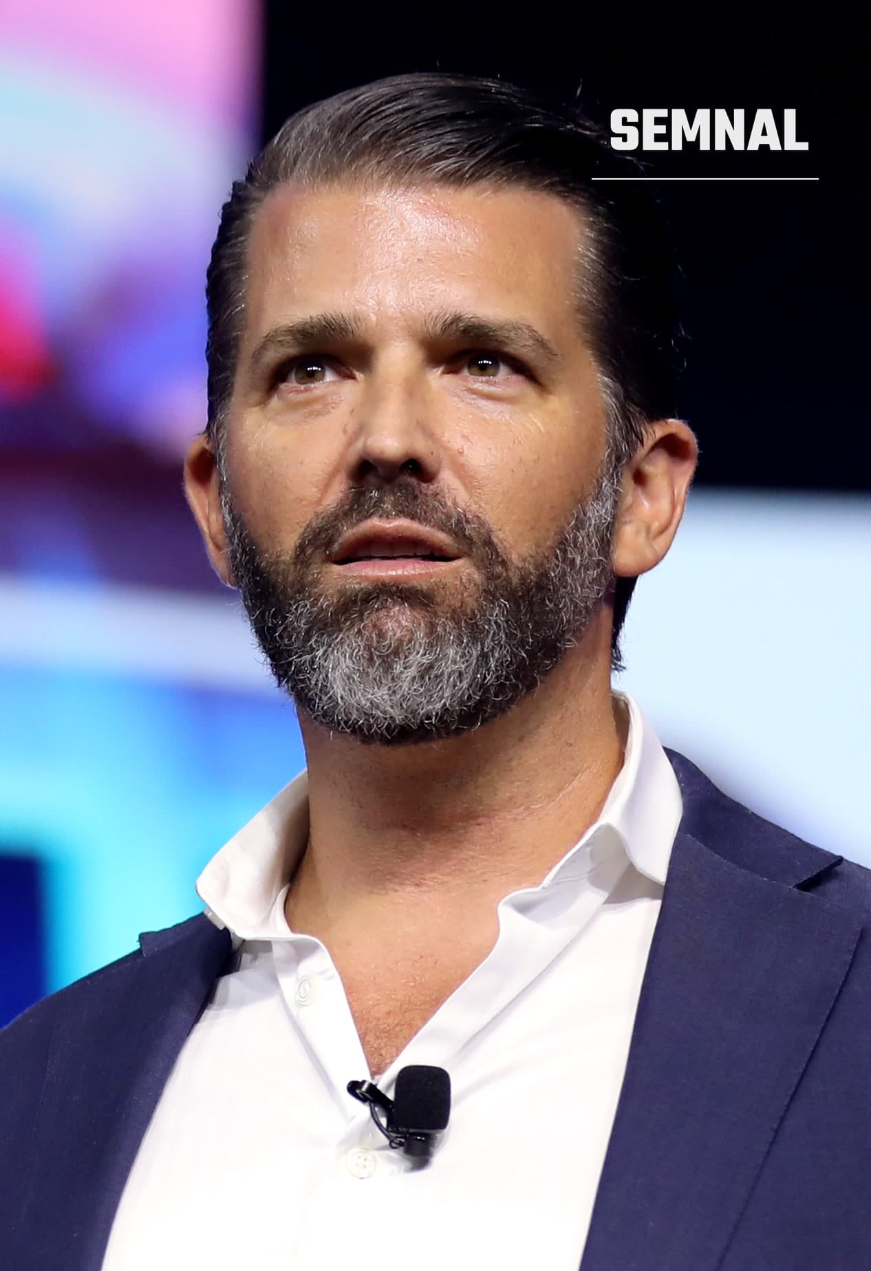 Donald Trump Jr., în sacou bleumarin și cămașă albă, cu microfon lavalier, vorbind pe scenă la un eveniment (Foto: Gage Skidmore from Surprise, AZ, United States of America)
