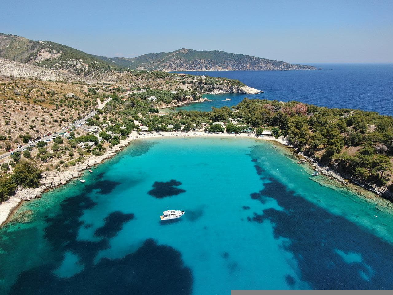 Plajă cu apă turcoaz și dealuri împădurite pe insula grecească Thassos