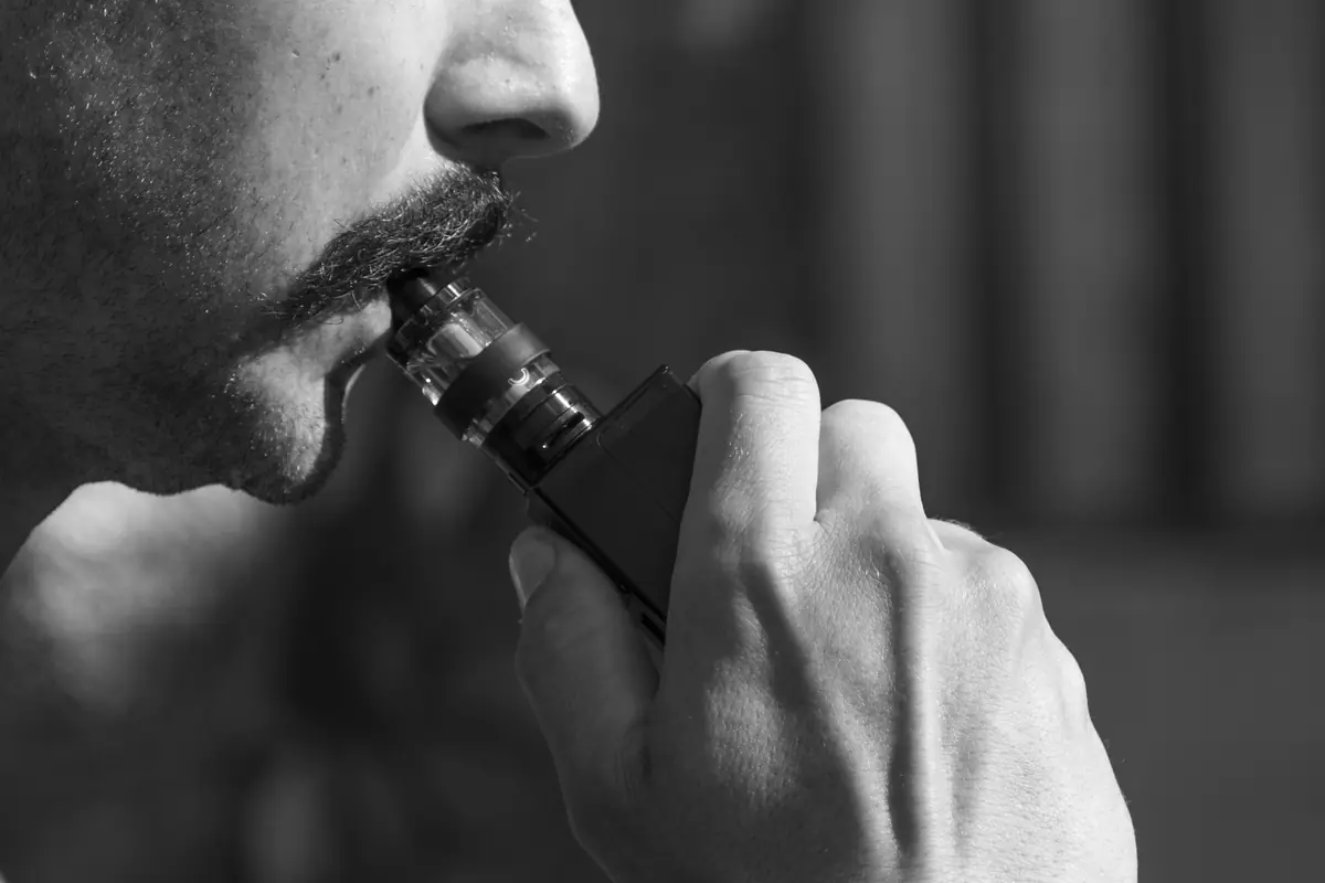 Bărbat inhalând dintr-o țigară electronică, portret alb-negru