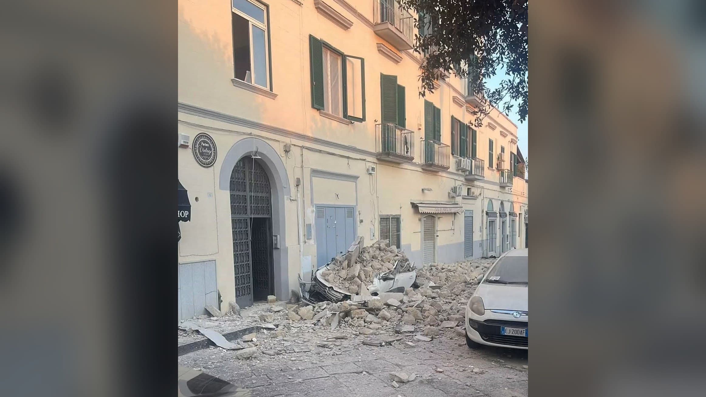 Moloz și o mașină strivită sub dărâmăturile căzute de pe fațada unei clădiri, pe o stradă din Pozzuoli, după cutremurul de 4,7 din zona Campi Flegrei