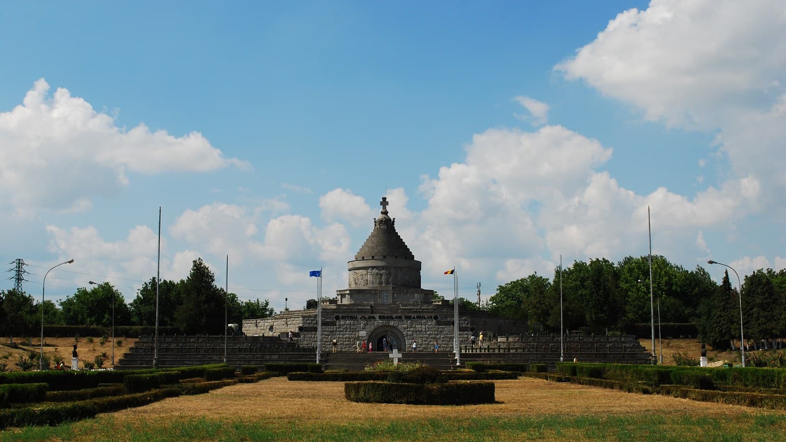 Mausoleul Eroilor de la Mărășești, văzut din parcul de la intrare, cu treptele în terase și drapelele României și Uniunii Europene