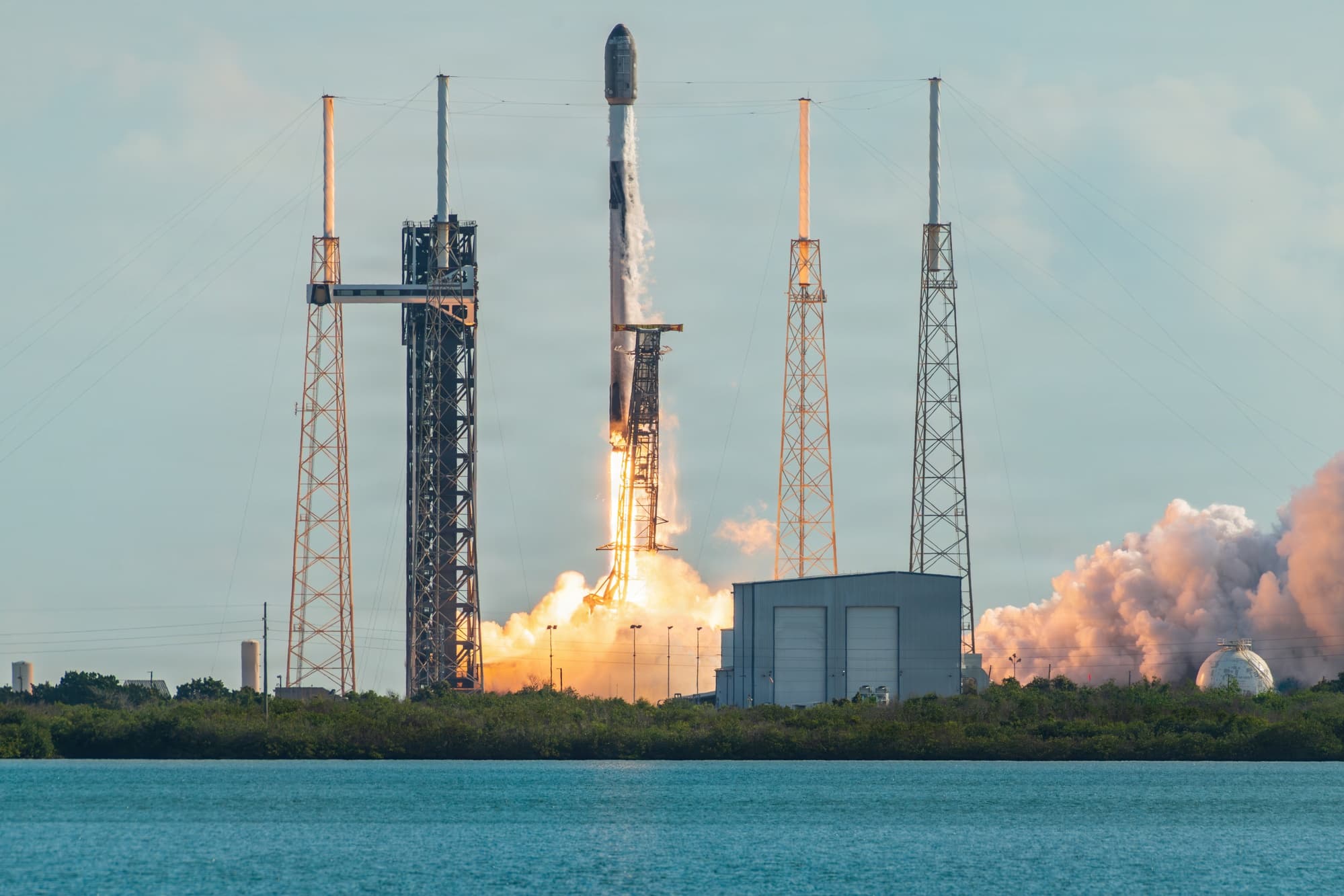 O rachetă SpaceX Falcon 9 se ridică de pe rampa de lansare de la Cape Canaveral, cu un jet de flăcări portocalii sub ea, pe cerul nopții.