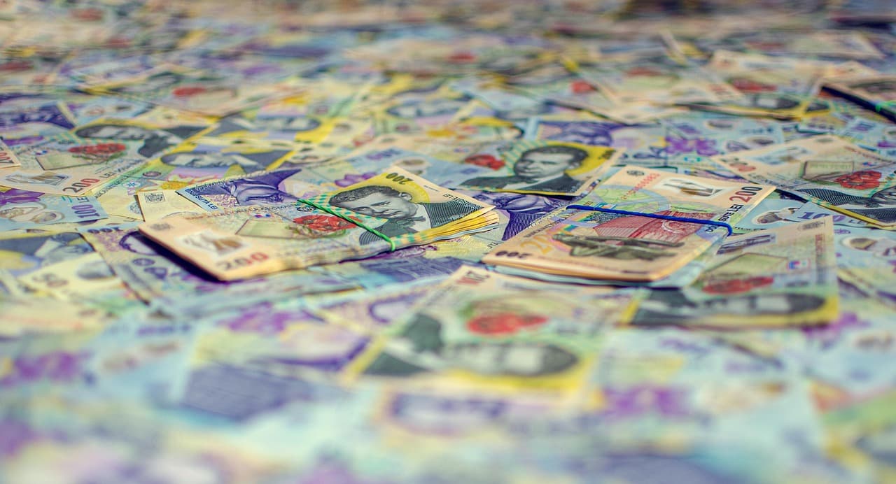 Bancnote de 100 și 200 de lei românești, așezate în teancuri pe o suprafață
