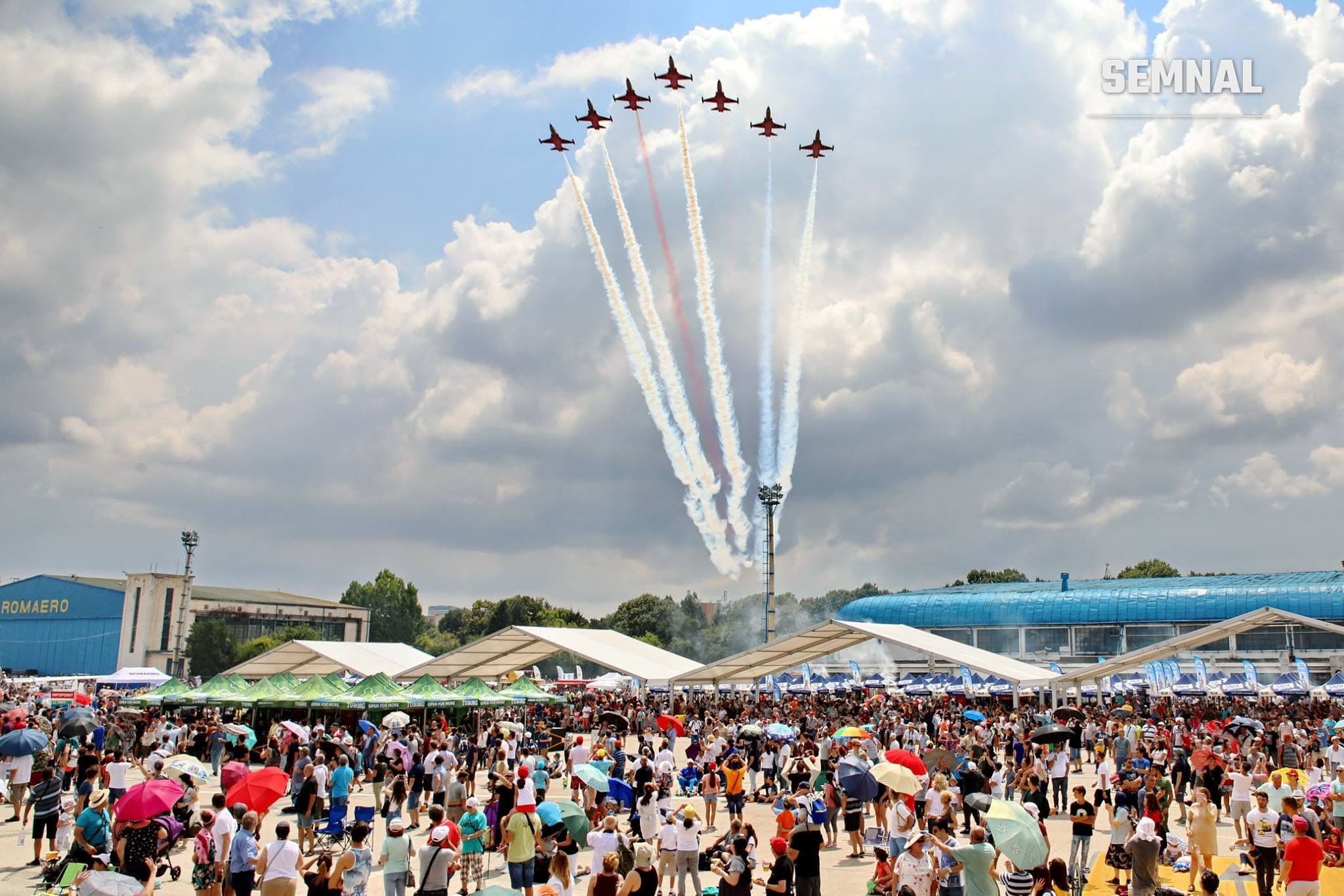 Formația Turkish Stars survolează în formație platforma Romaero de la Aeroportul Băneasa, cu trene de fum roșu și alb, în fața publicului adunat la mitingul aviatic