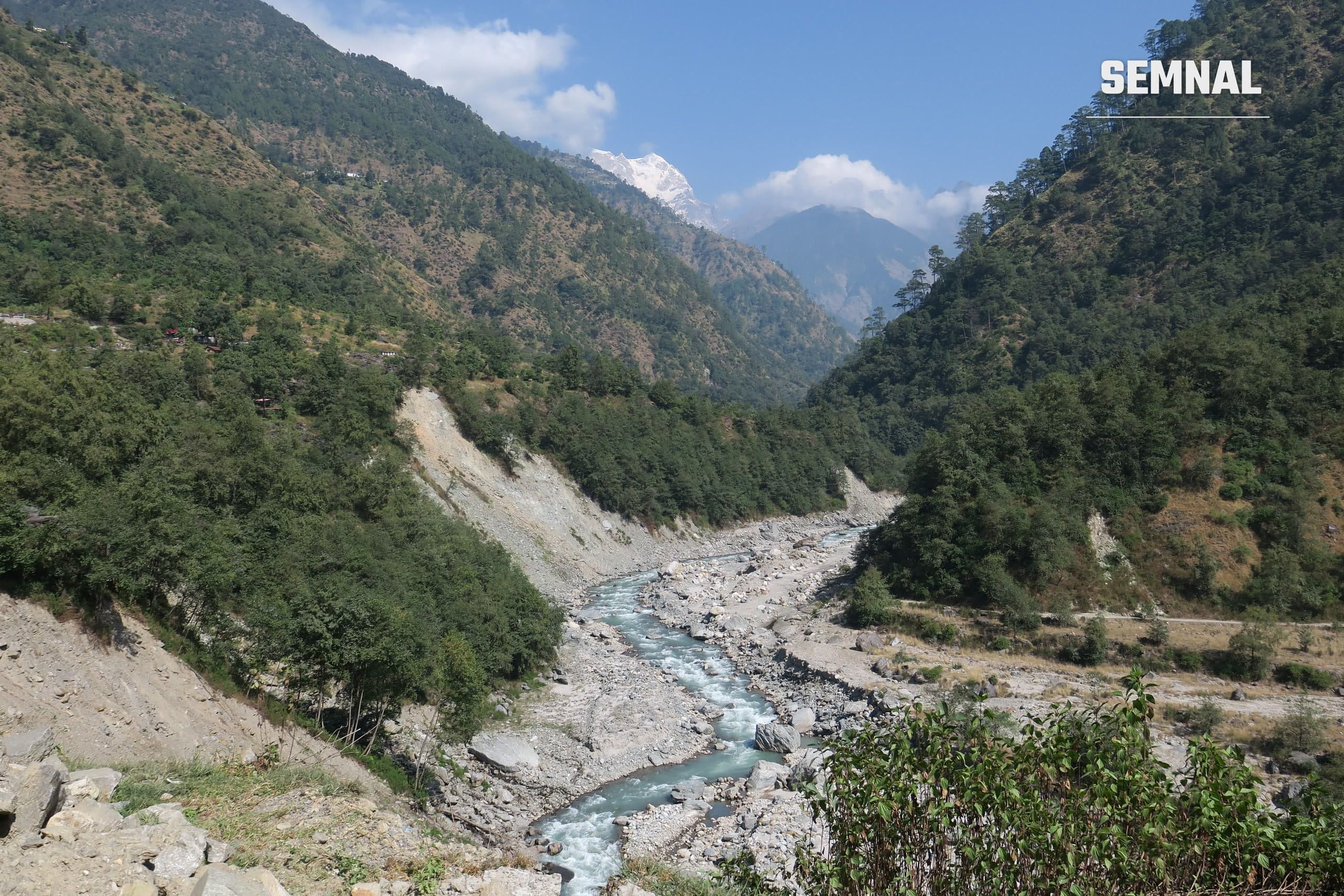Râu montan în Himalaya, cu văi verzi și vârfuri înzăpezite în fundal