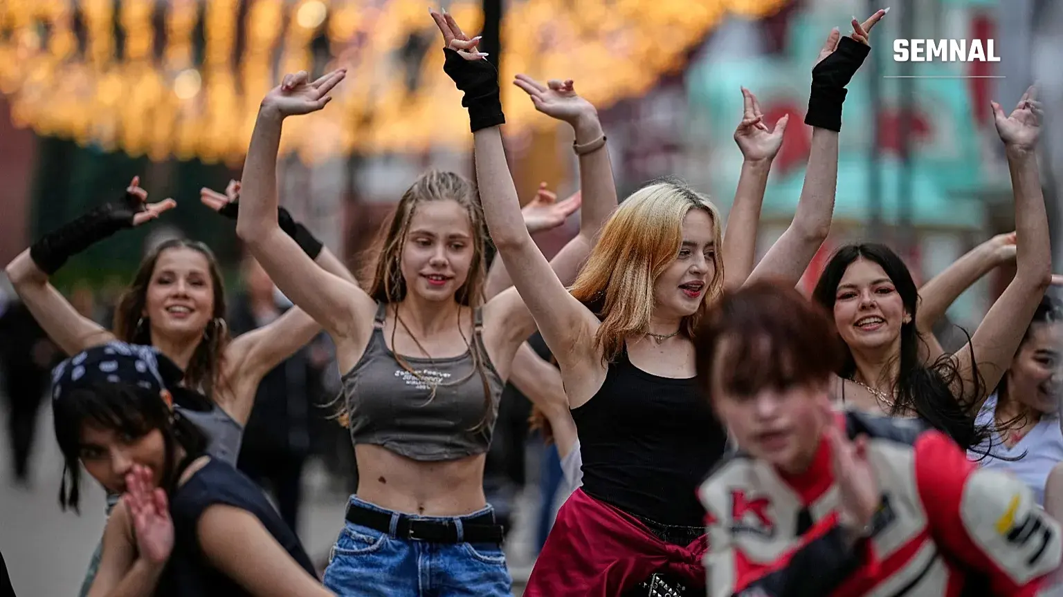 Grup de tinere într-un flashmob stradal, dansând cu brațele ridicate — imagine ilustrativă generică pentru trendurile de dans virale de tip „aura farming”