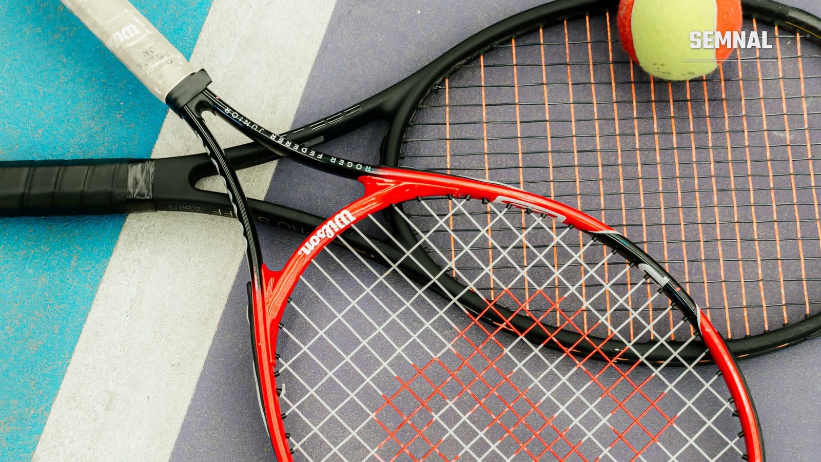 Rachetă de tenis și mingi galbene, așezate în colțul unui teren cu suprafață albastră