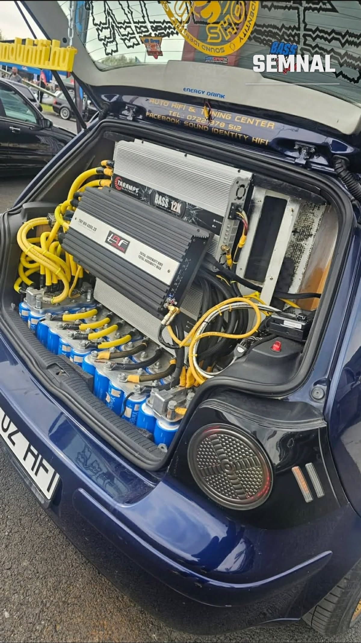 Portbagajul unui Volkswagen Golf 4 albastru, plin cu amplificatoare Taramps și TRF montate peste un banc de 48 de celule LTO conectate cu cabluri galbene