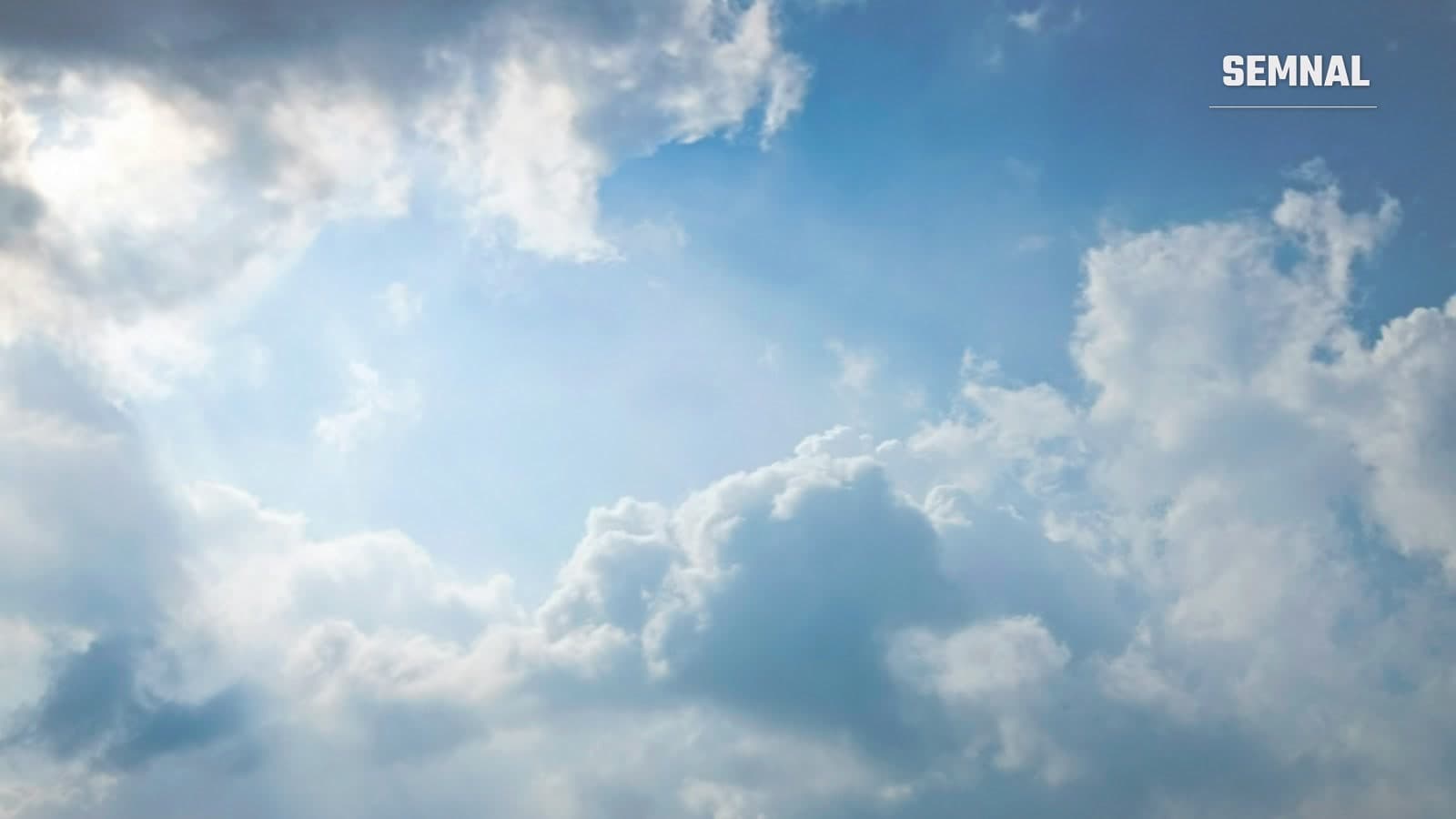 Raze de soare pătrunzând printre nori albi pe un cer albastru