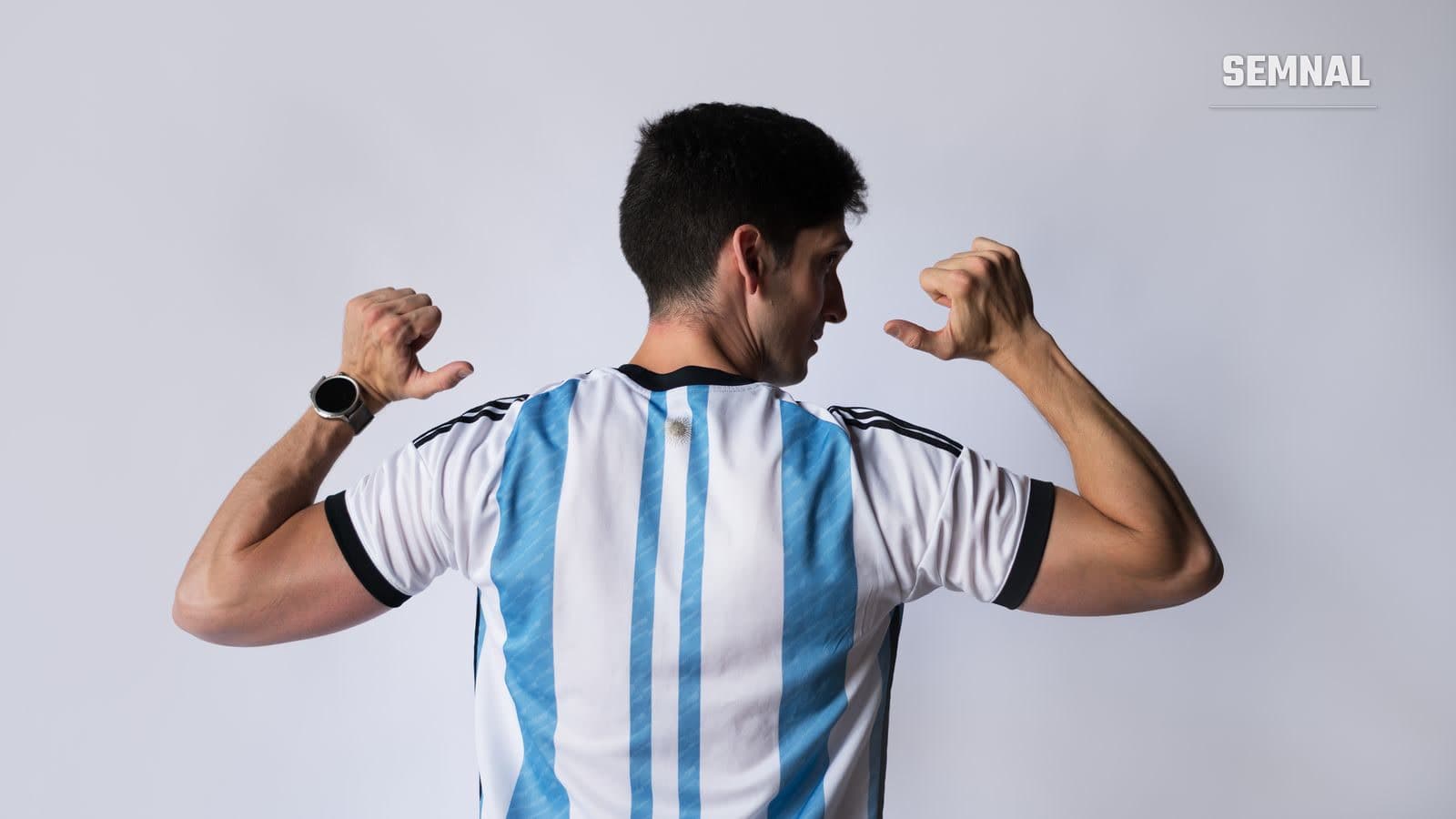 Bărbat văzut din spate, purtând tricoul naționalei Argentinei, cu brațele ridicate