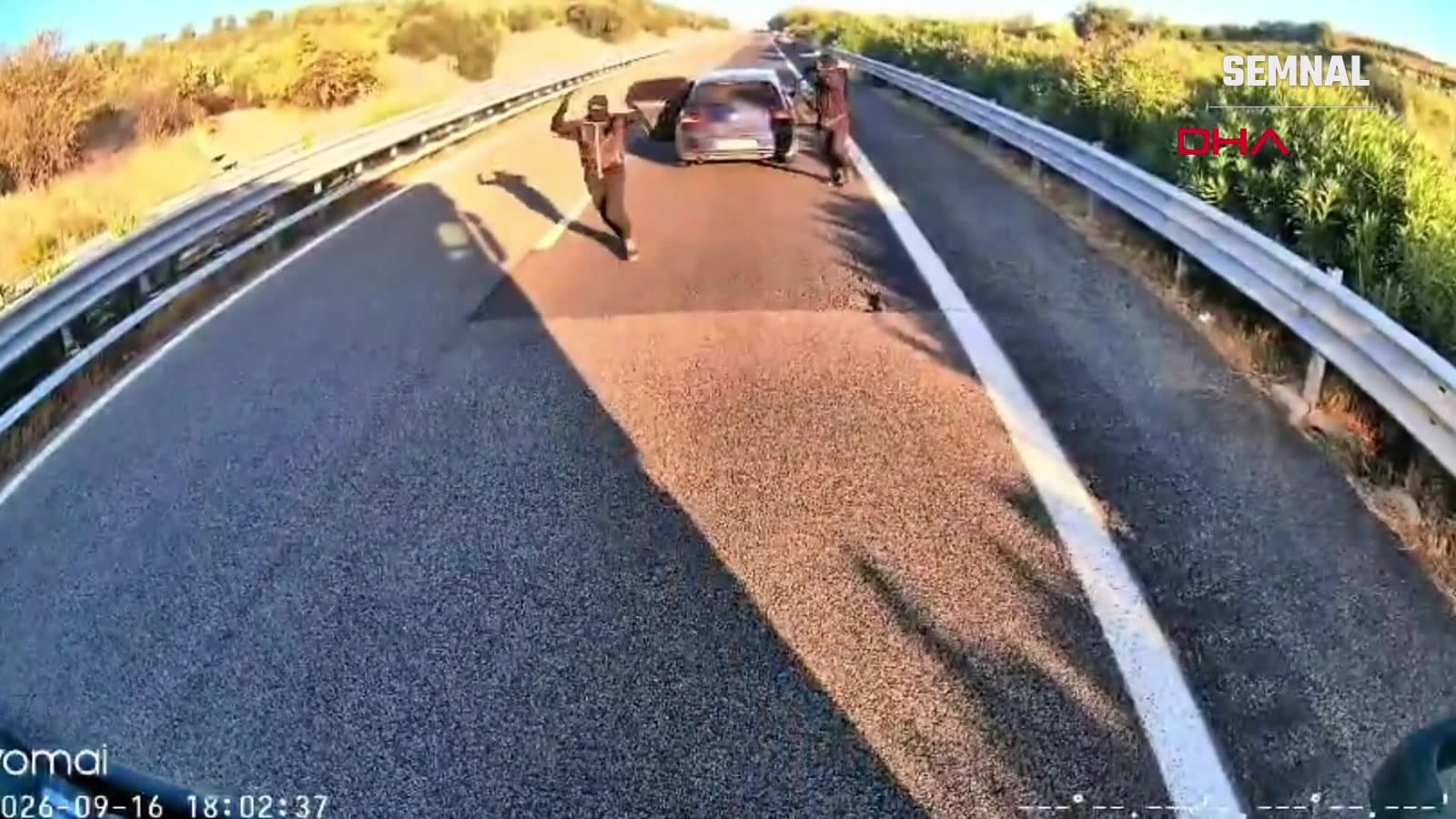 Bărbat mascat, cu armă lungă ridicată, în mijlocul autostrăzii A14 din Italia, lângă autoturismul care a blocat camionul — cadru din camera de bord