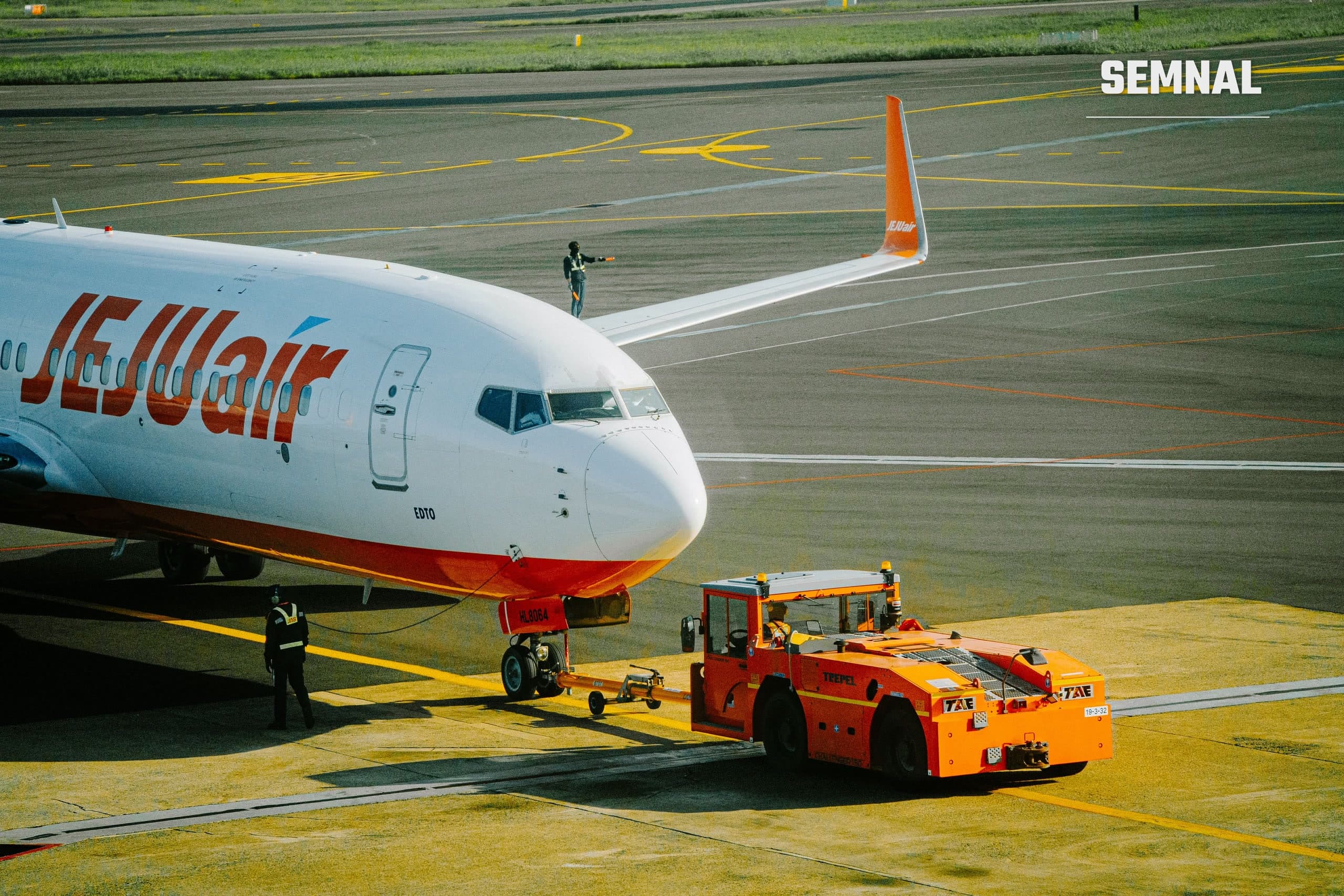 Personal de deservire la sol lucrează lângă un avion de pasageri pe platforma unui aeroport.