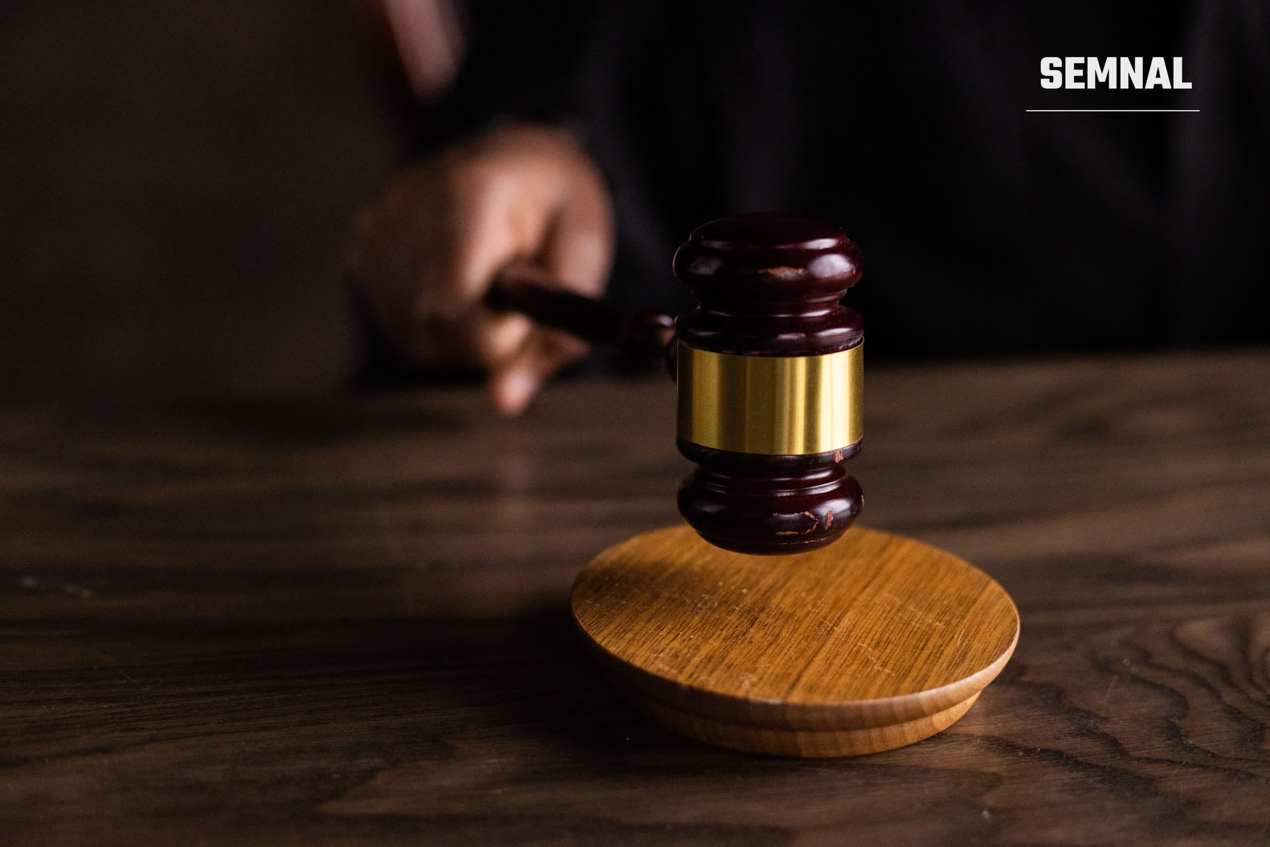 Ciocănel de judecător pe o masă din lemn, alături de documente, simbol al unei anchete judiciare în desfășurare
