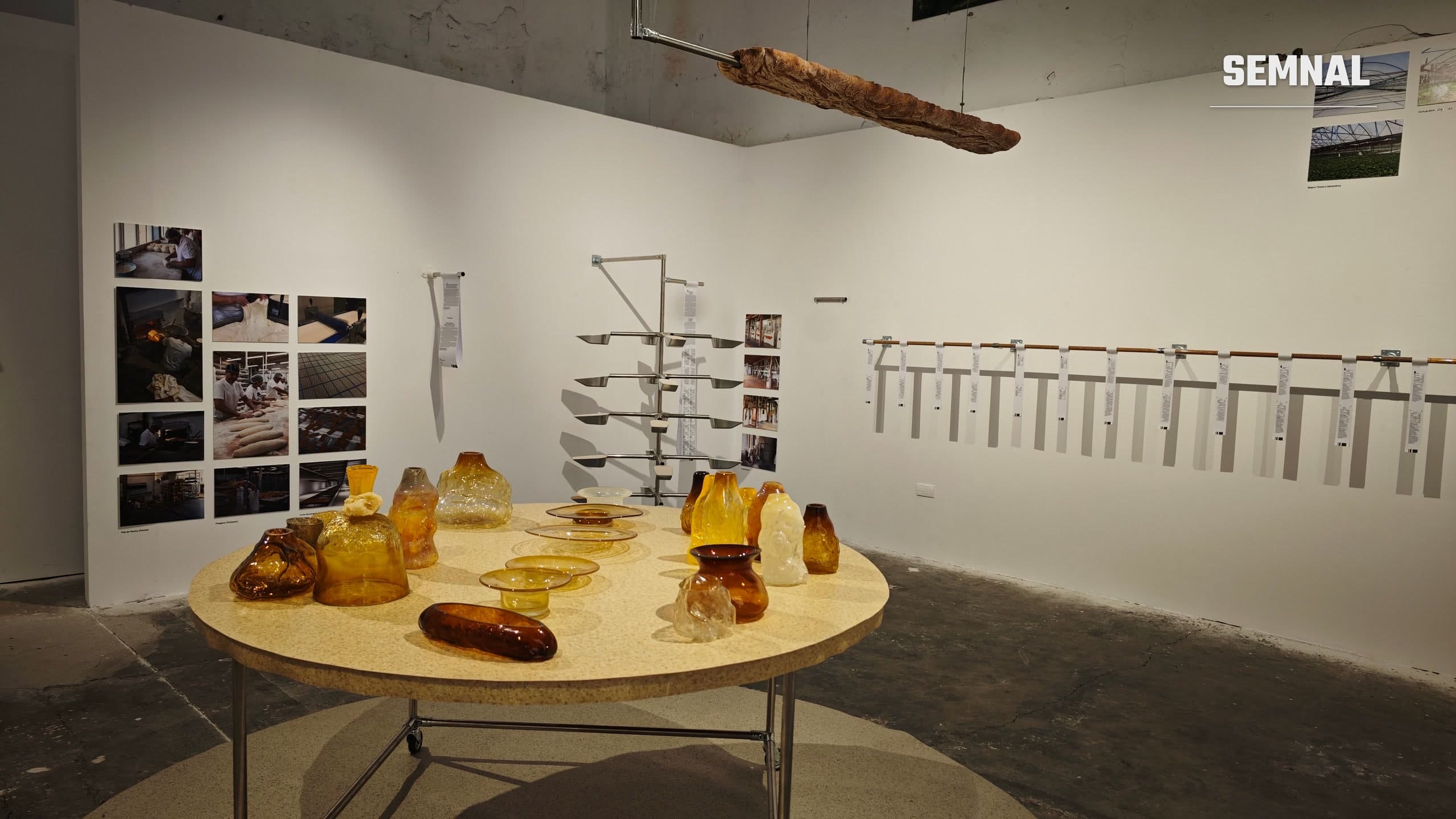 Masă rotundă cu obiecte din sticlă suflată în formă de pâine, în expoziția „Cinci hectare” de la FABER Timișoara